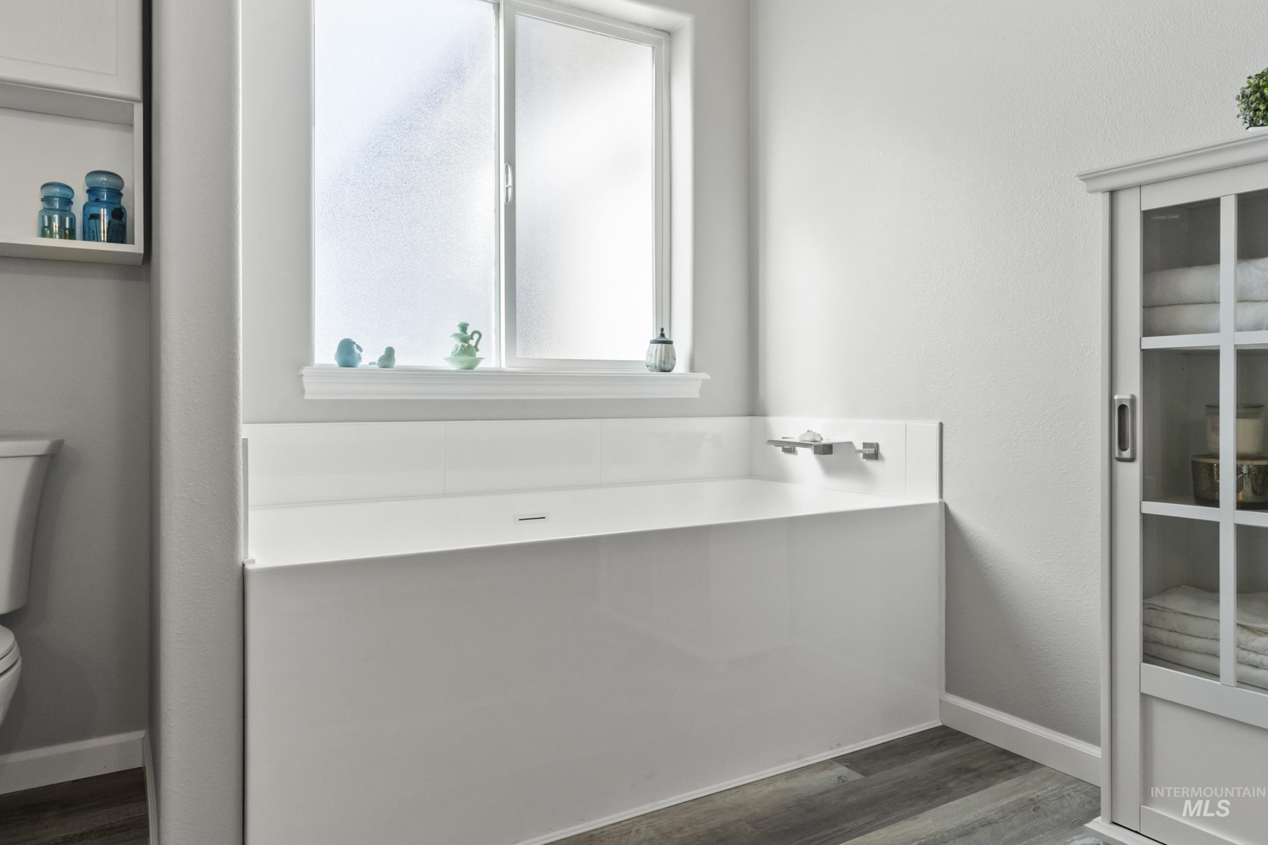 Full bath featuring dark wood-style flooring and a garden tub