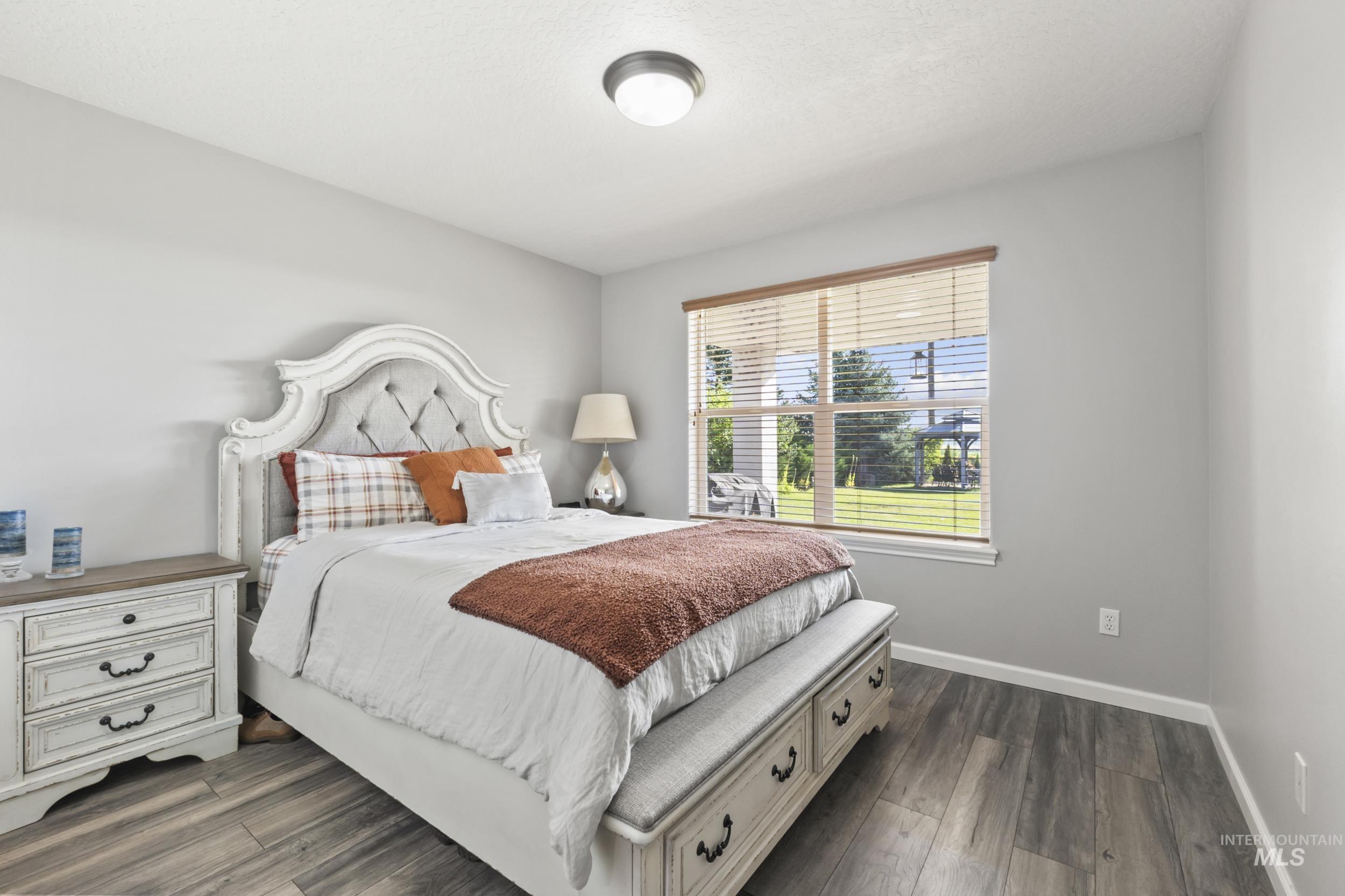 Bedroom with dark wood-style flooring and baseboards