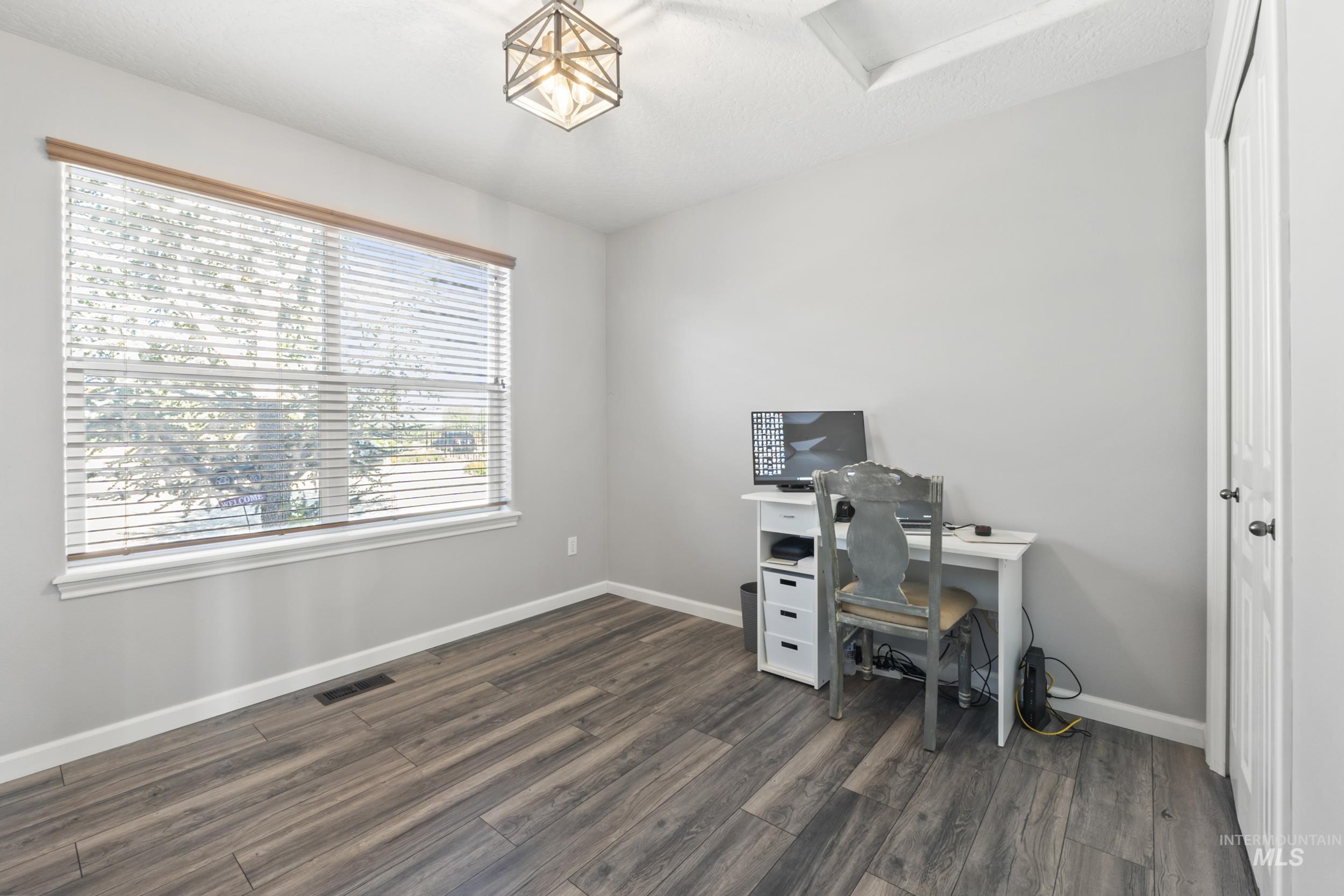 Office area with dark wood-style floors and attic access