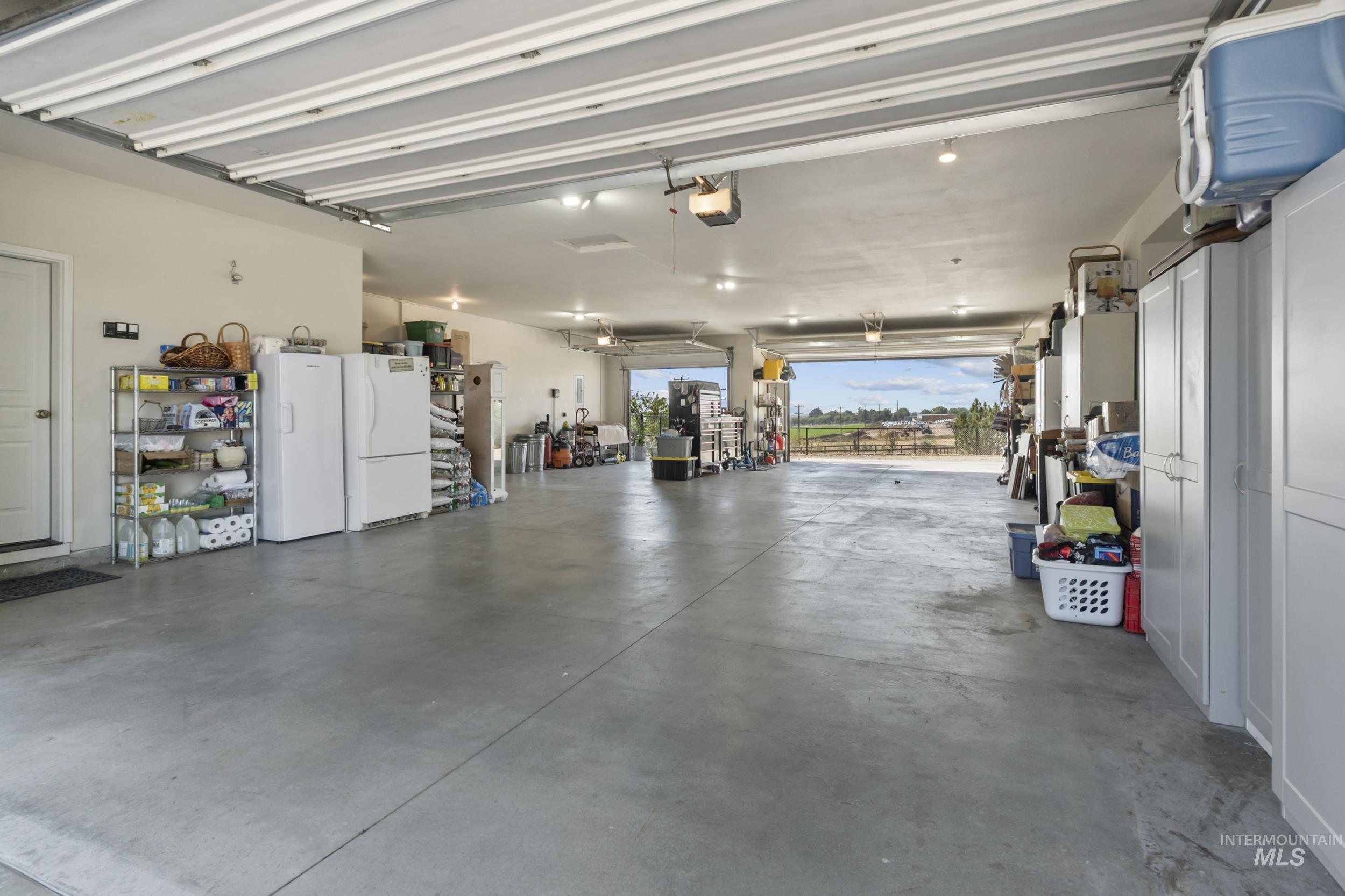 5-car drive-through garage, with space to spare.  Refrigerator, freezer, black shelving, and cabinets included.