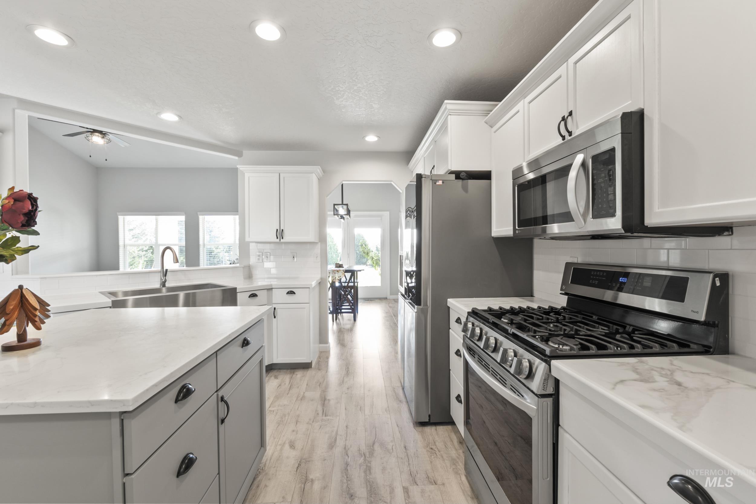 Kitchen with stainless steel appliances, tasteful backsplash, ceiling fan, white cabinetry, and recessed lighting