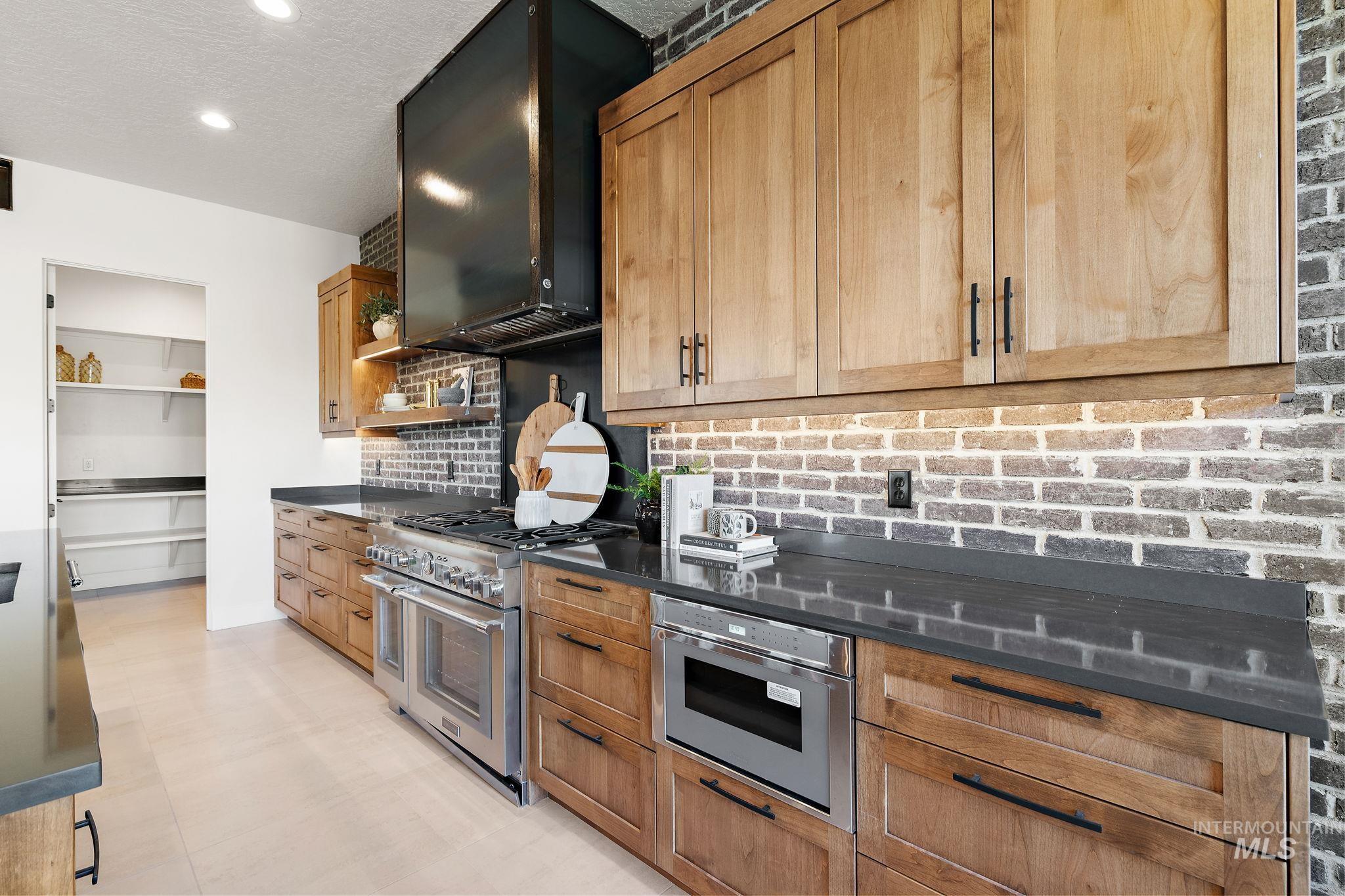 Kitchen featuring appliances with stainless steel finishes, open shelves, decorative backsplash, a textured ceiling, and range hood