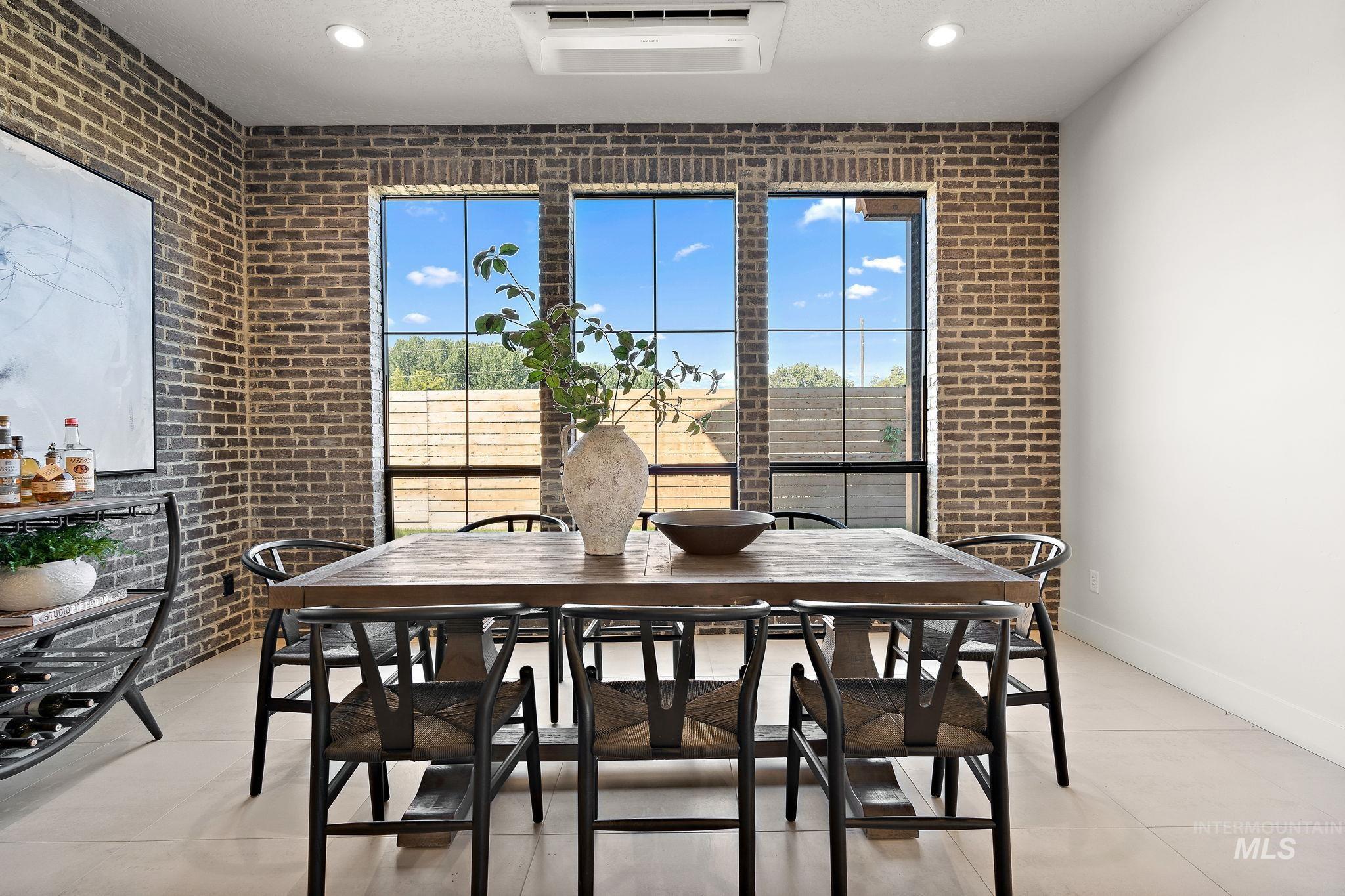 Dining area featuring brick wall, light tile patterned floors, and a wall mounted air conditioner