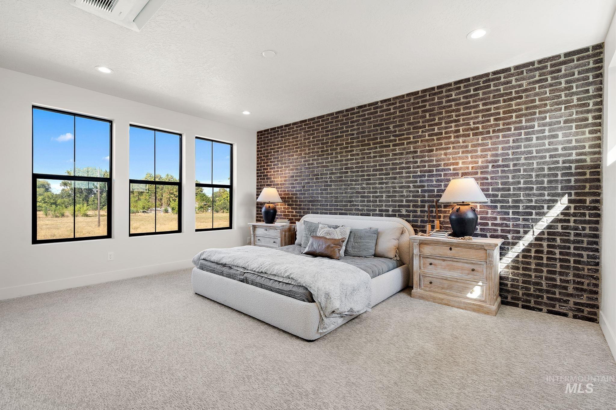 Bedroom with brick wall, light colored carpet, recessed lighting, and a textured ceiling
