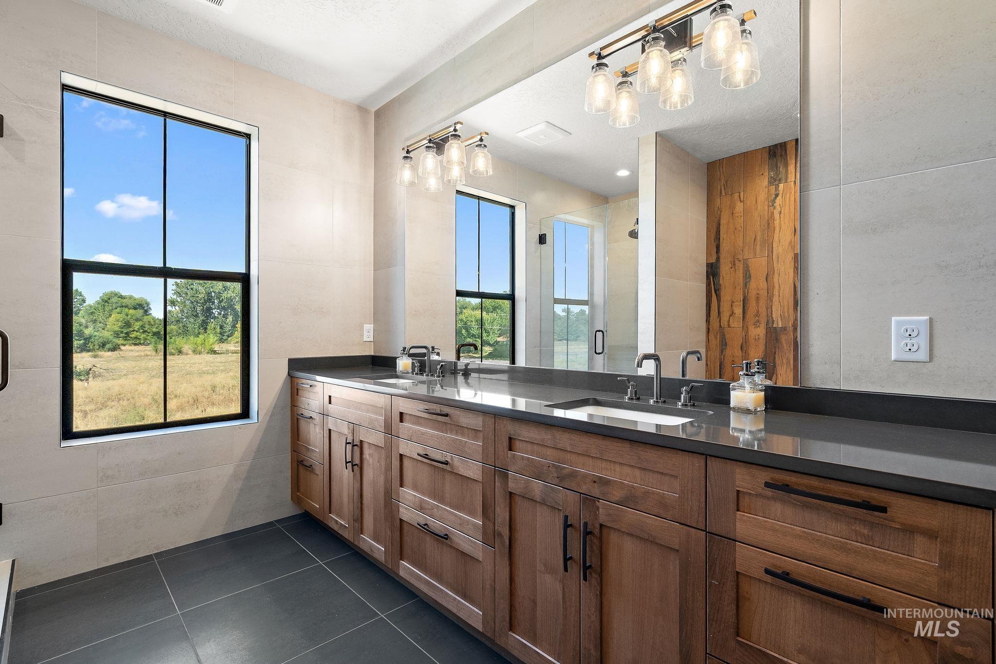 Bathroom with tile walls, double vanity, a stall shower, dark tile patterned flooring, and a textured ceiling
