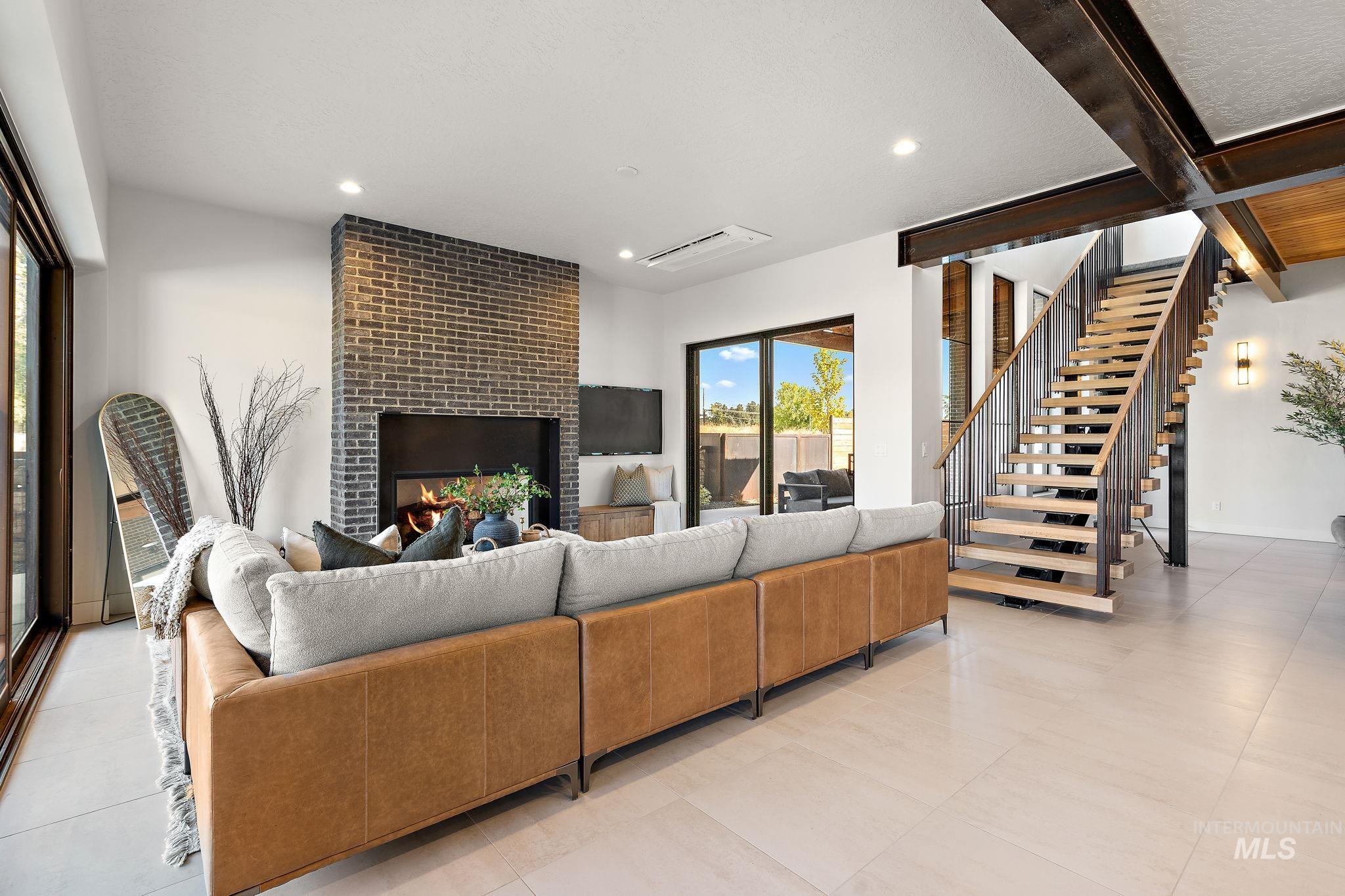 Living area featuring a brick fireplace, stairs, light tile patterned floors, beam ceiling, and recessed lighting