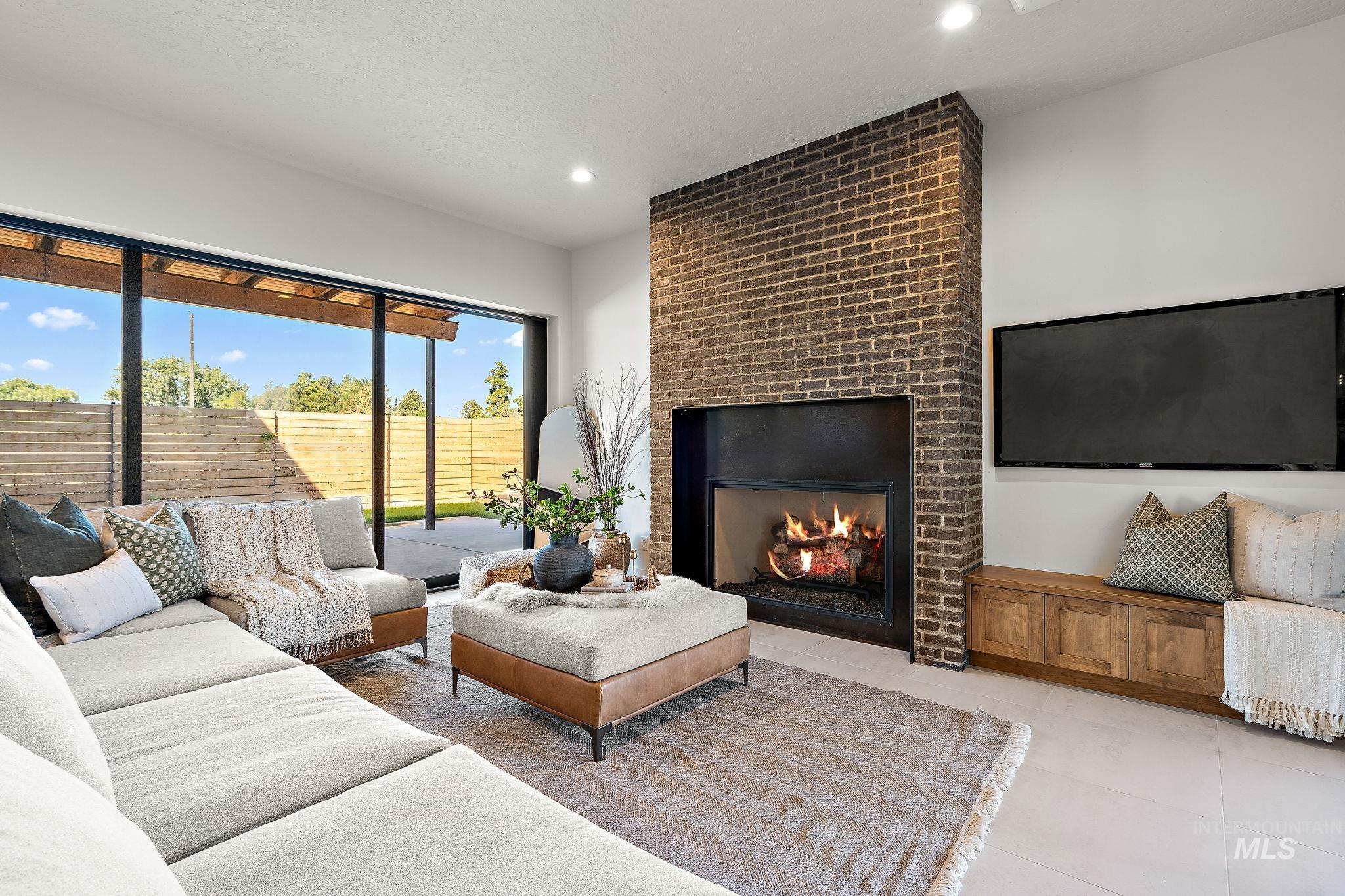 Living room featuring a brick fireplace, light tile patterned floors, a textured ceiling, and recessed lighting