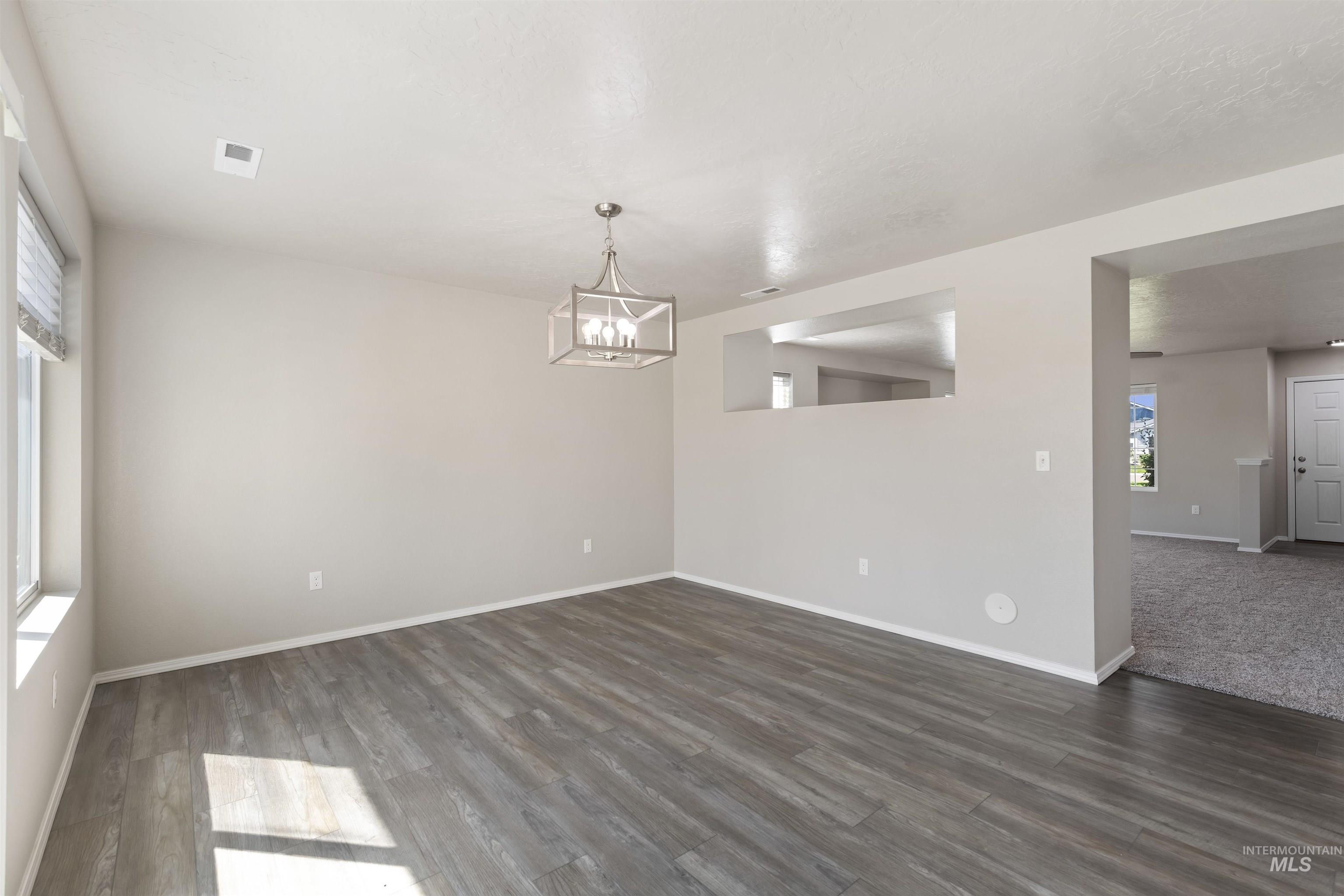 Unfurnished room with dark wood-style flooring and a chandelier