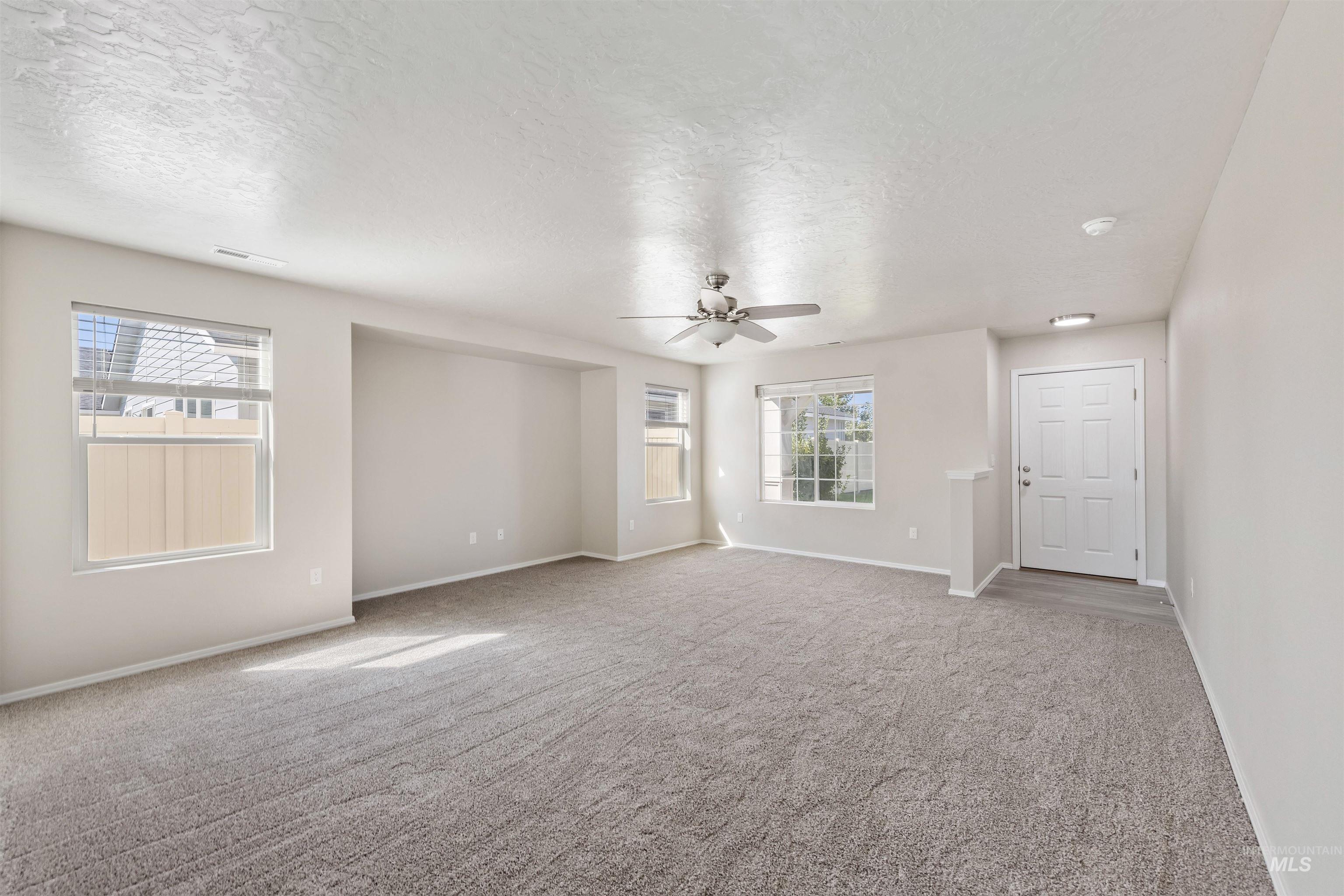 Empty room featuring light colored carpet and a textured ceiling