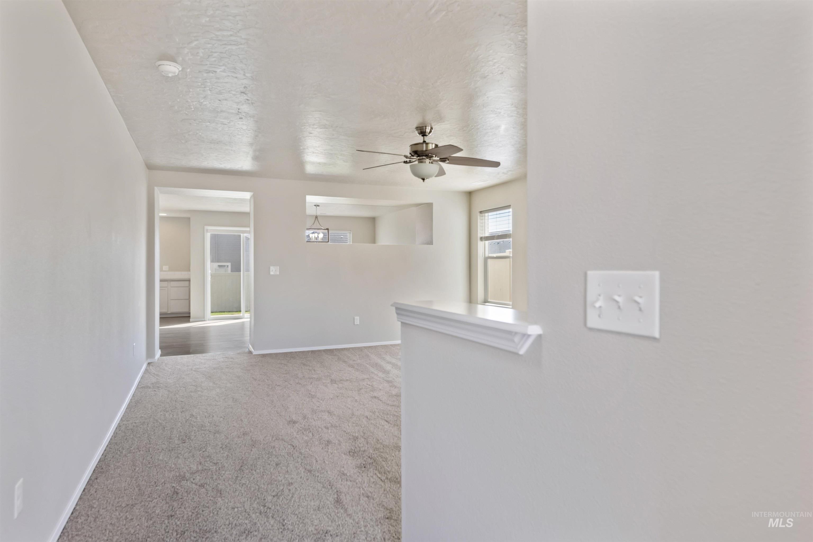 Empty room featuring light carpet, ceiling fan, and a textured ceiling