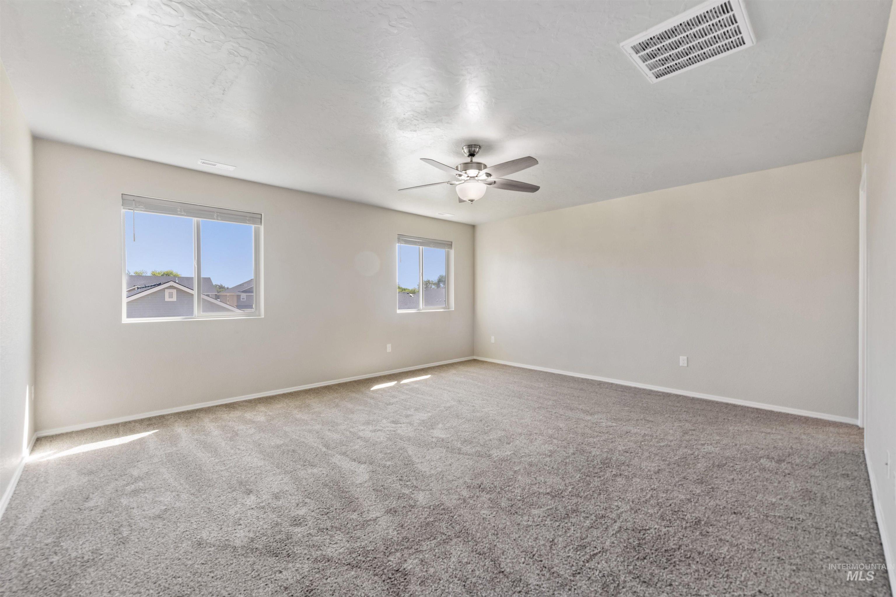 Unfurnished room with light carpet, ceiling fan, and a textured ceiling