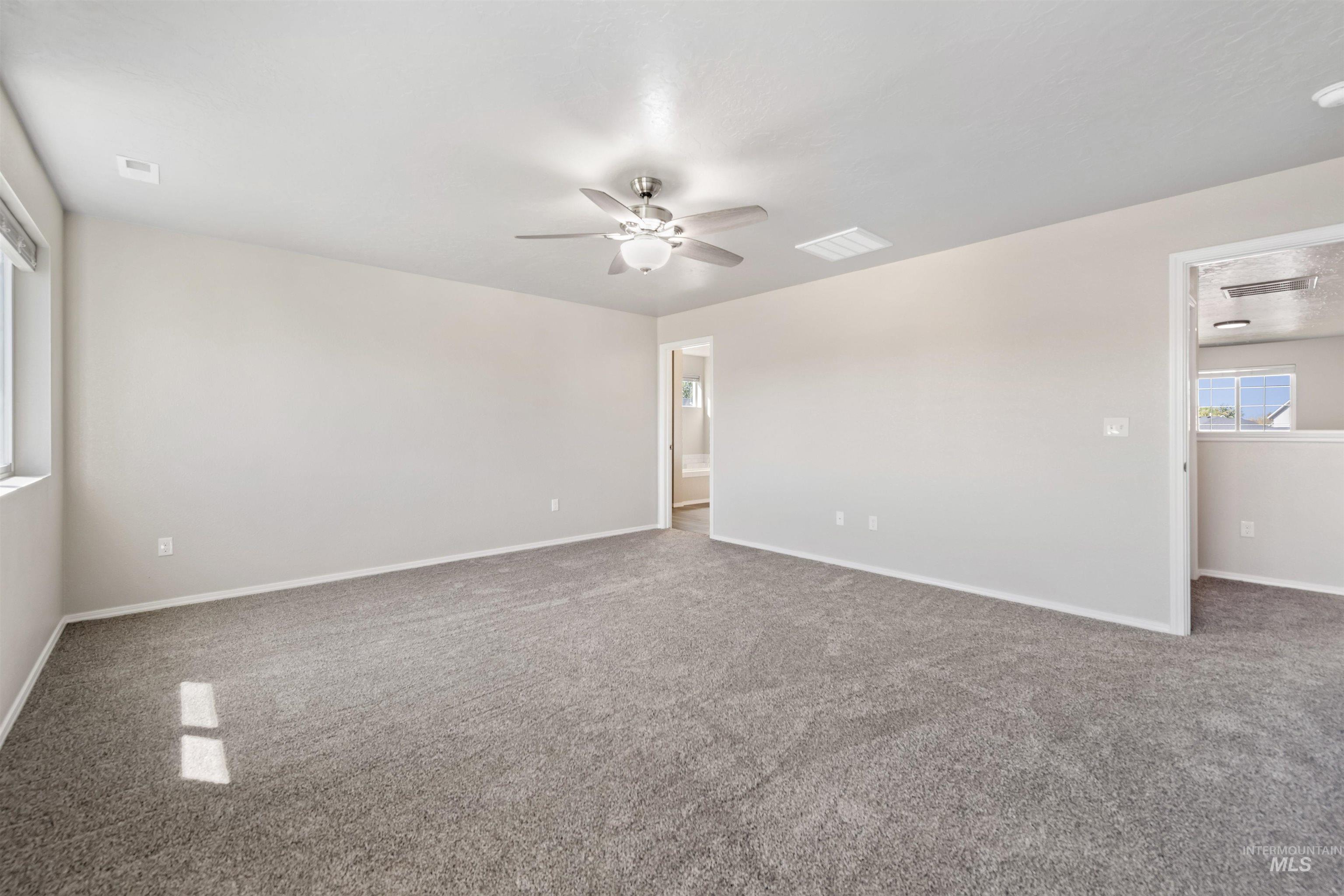 Carpeted spare room featuring baseboards and ceiling fan