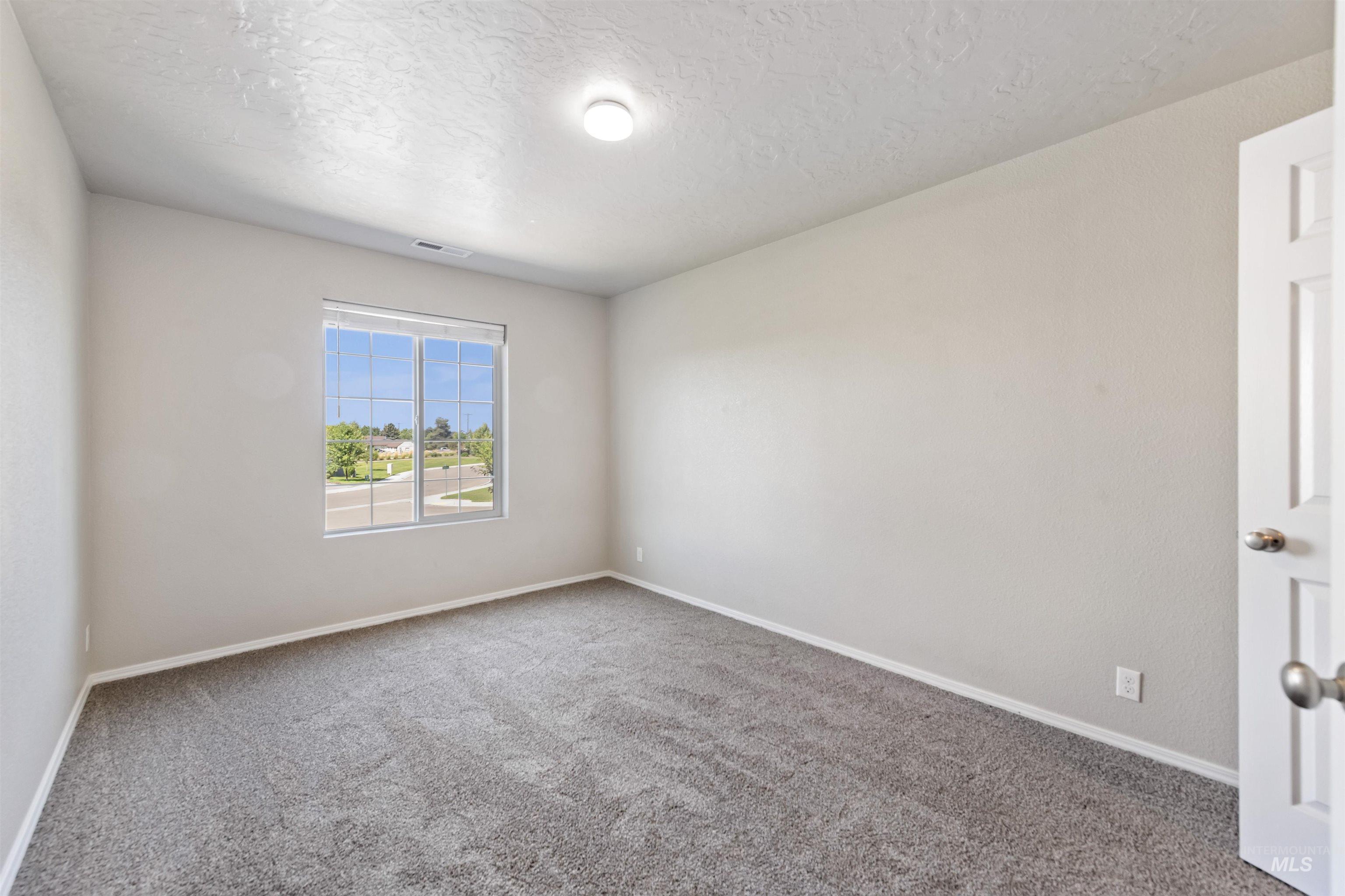 Carpeted spare room featuring baseboards and a textured ceiling