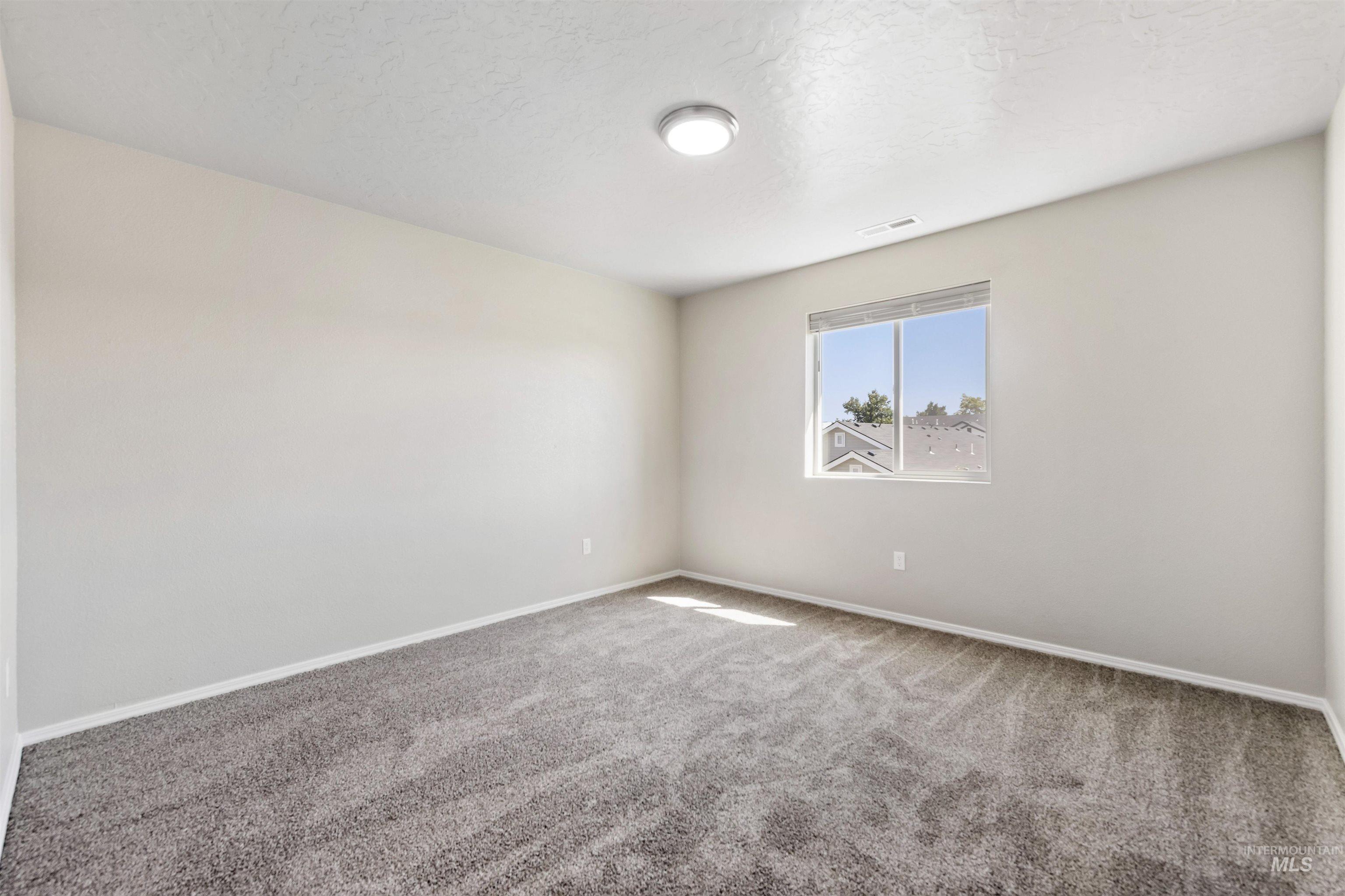Carpeted empty room featuring baseboards and a textured ceiling