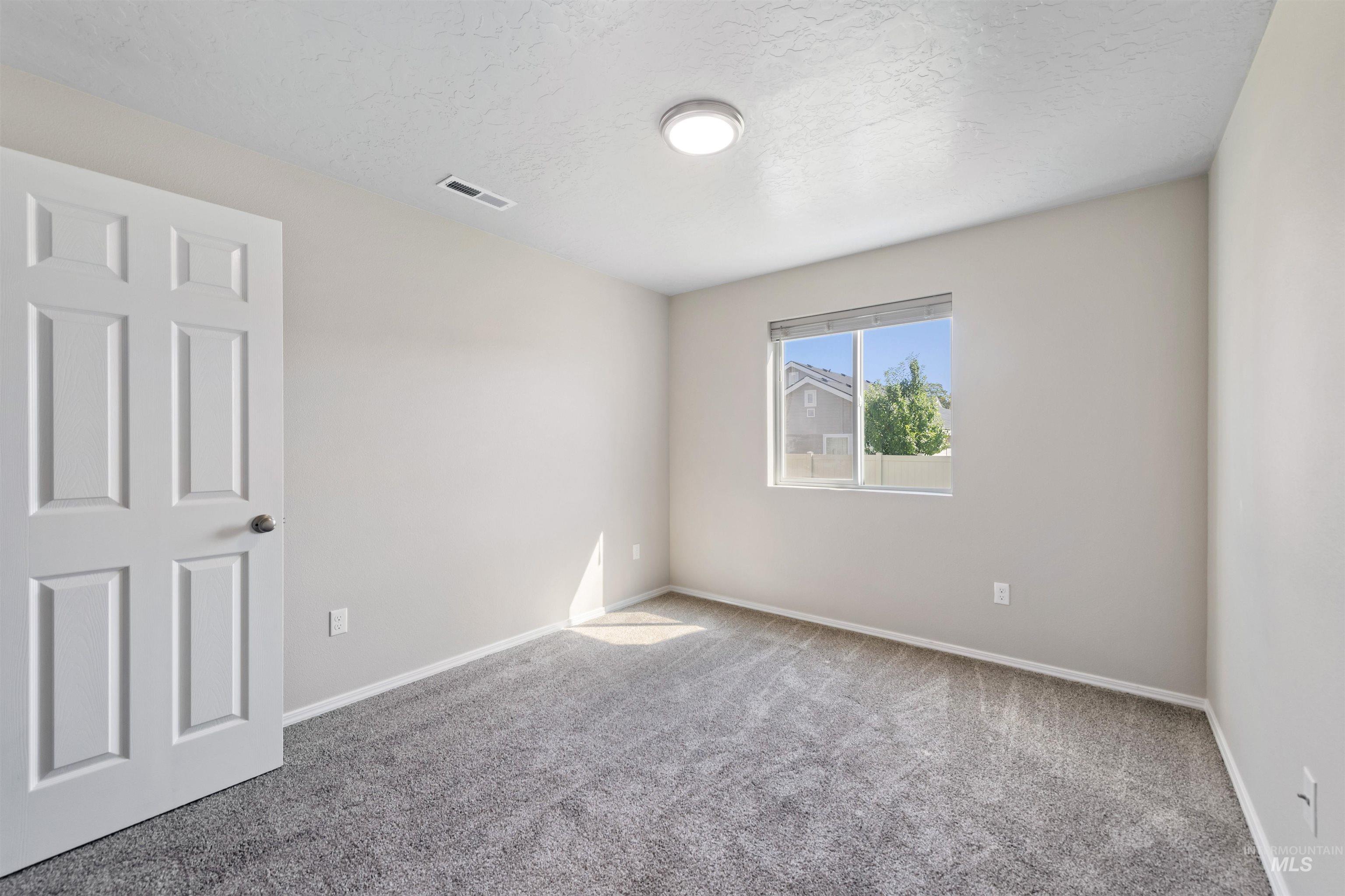 Carpeted spare room with baseboards and a textured ceiling