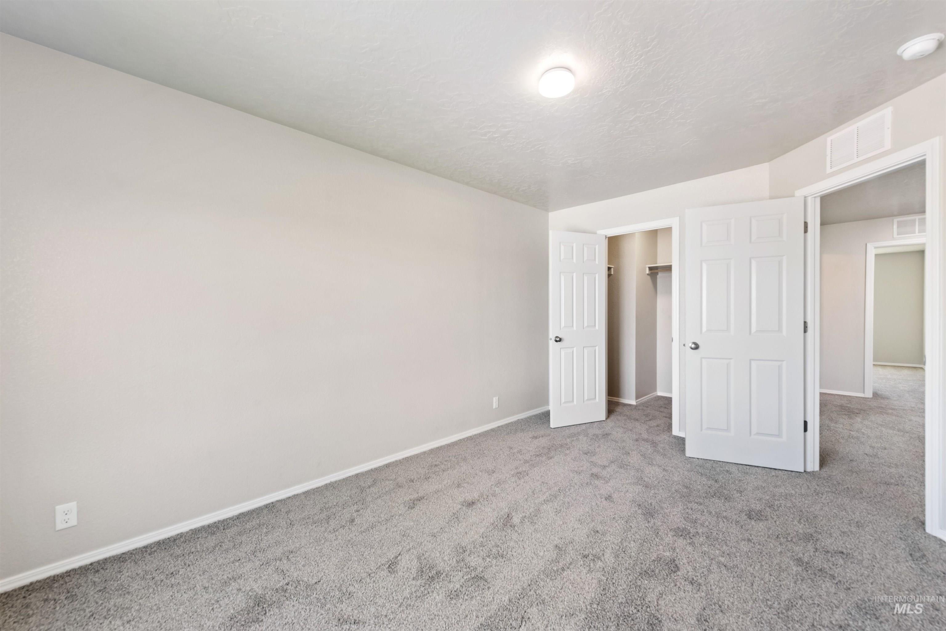 Unfurnished bedroom with carpet floors, a spacious closet, and a textured ceiling