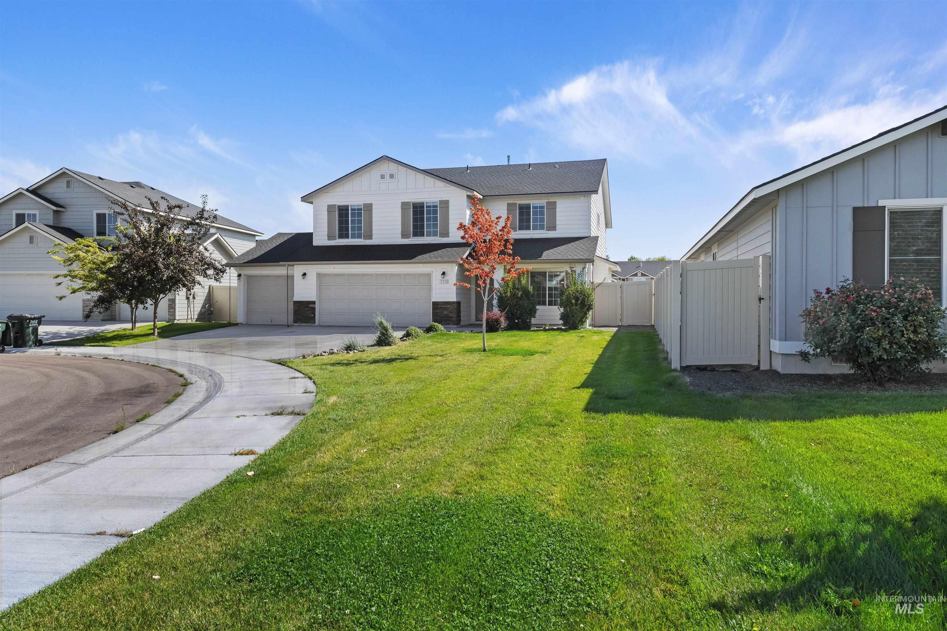 Traditional home with driveway, board and batten siding, an attached garage, a gate, and stone siding