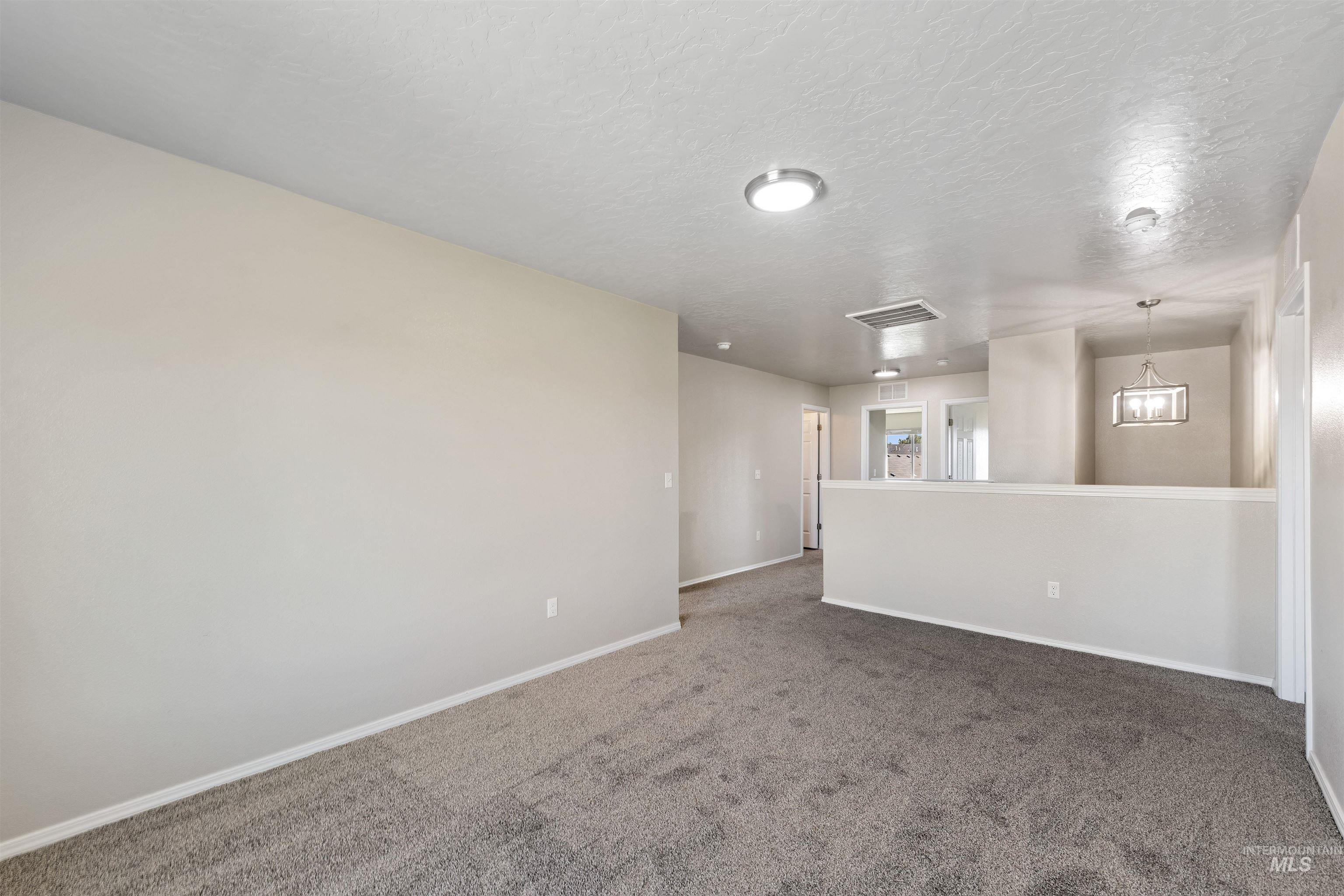Unfurnished room featuring dark carpet and a textured ceiling