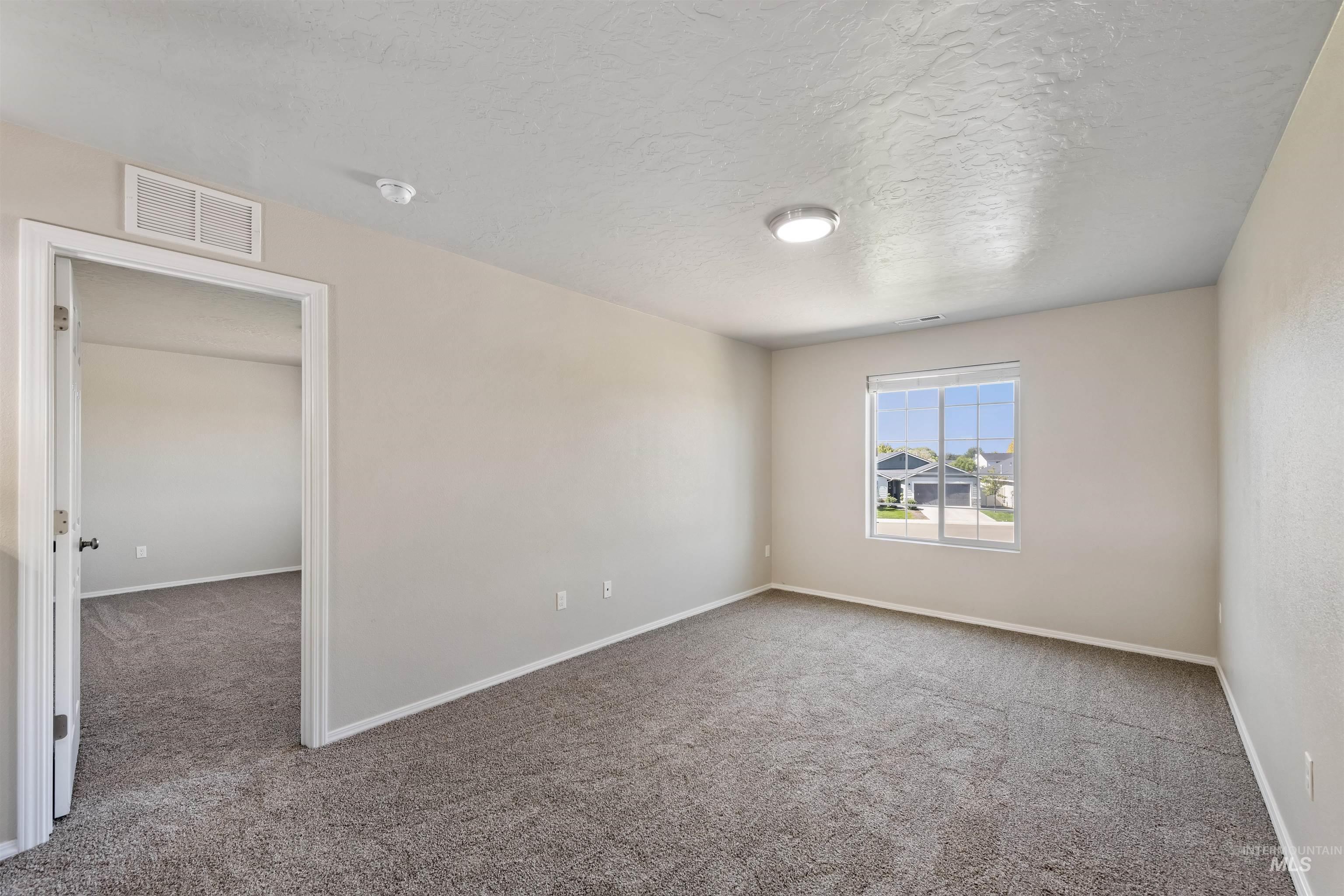 Unfurnished room with light colored carpet and a textured ceiling
