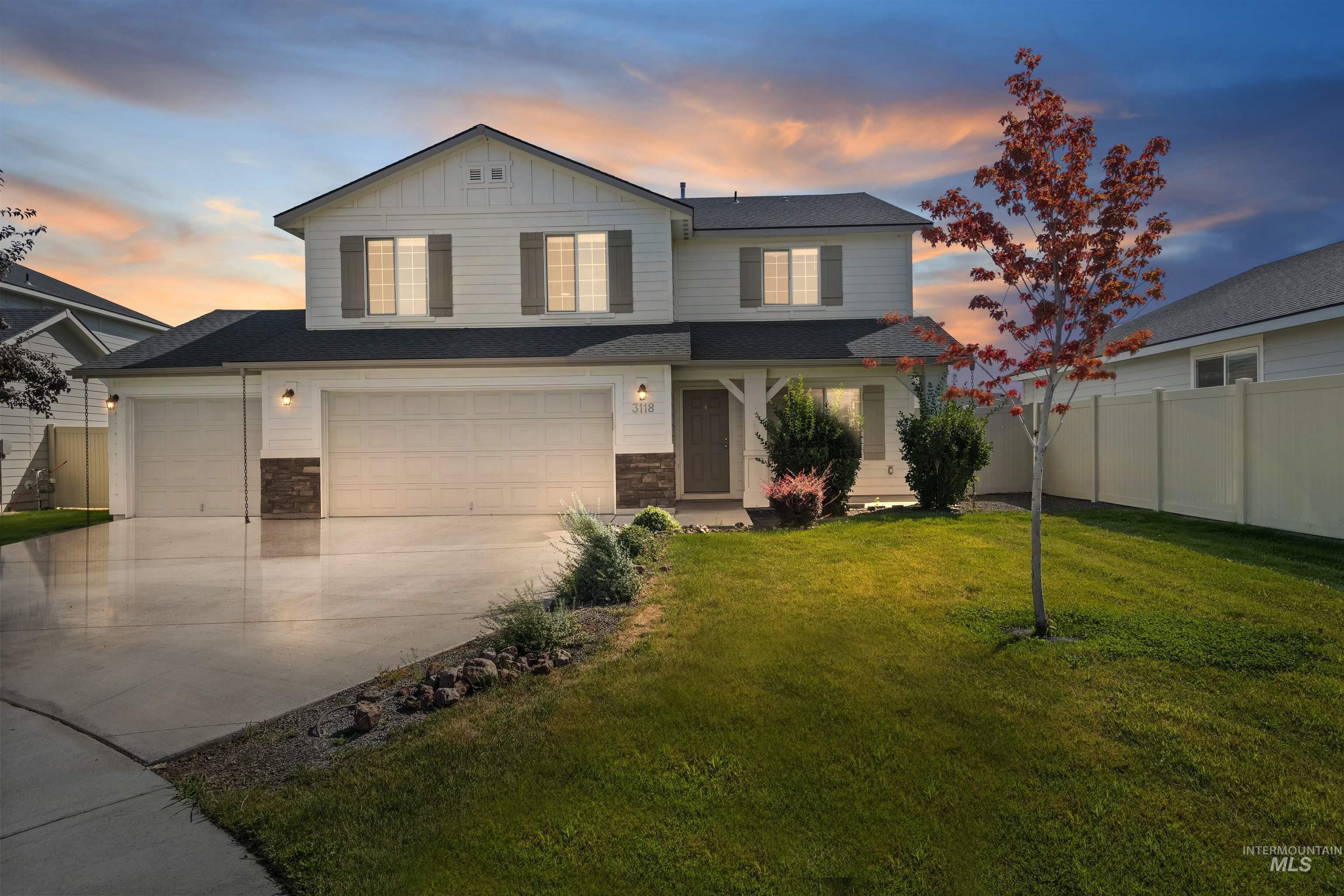 View of front of house featuring driveway, stone siding, board and batten siding, and an attached garage