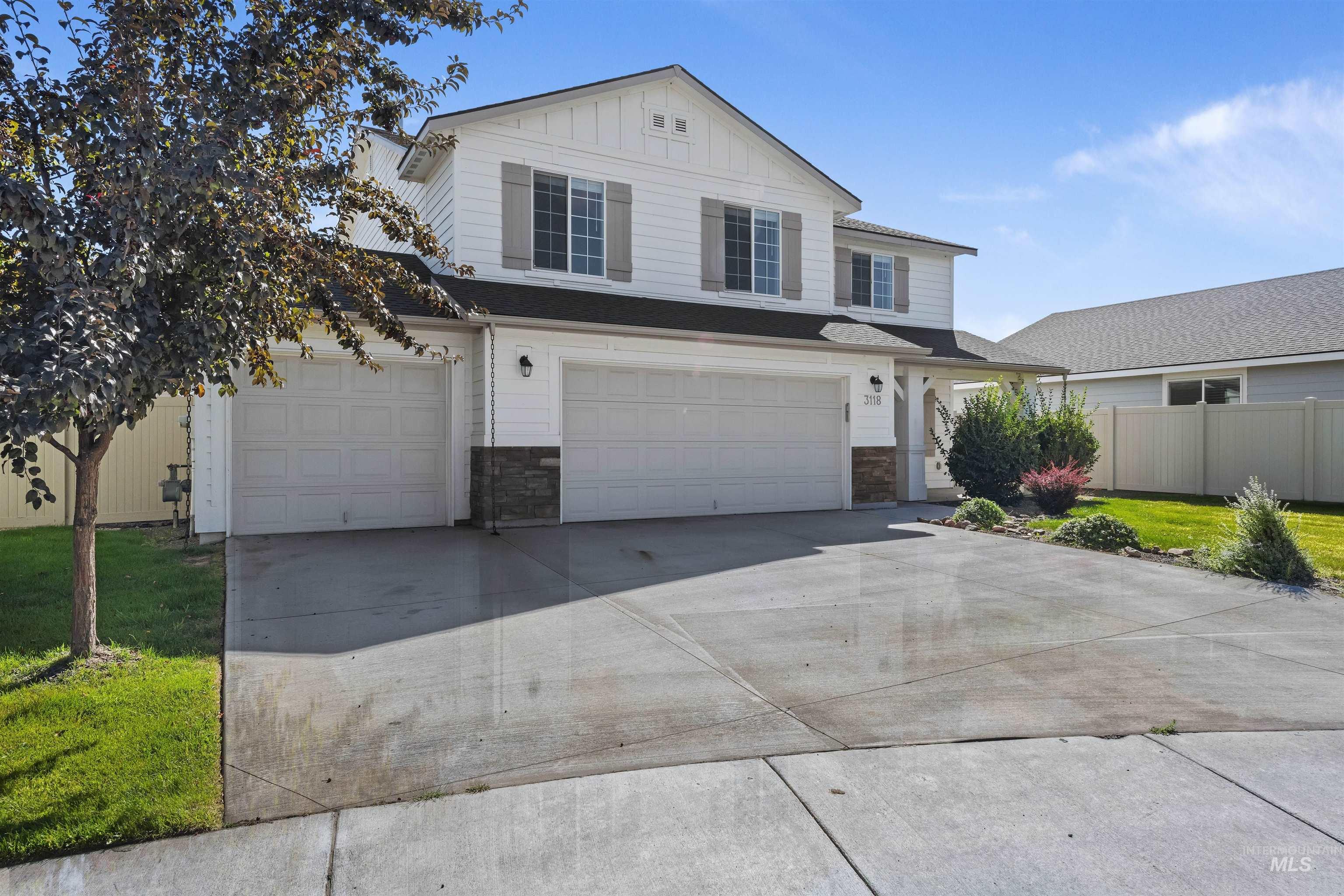 Traditional-style house featuring driveway, board and batten siding, an attached garage, and stone siding