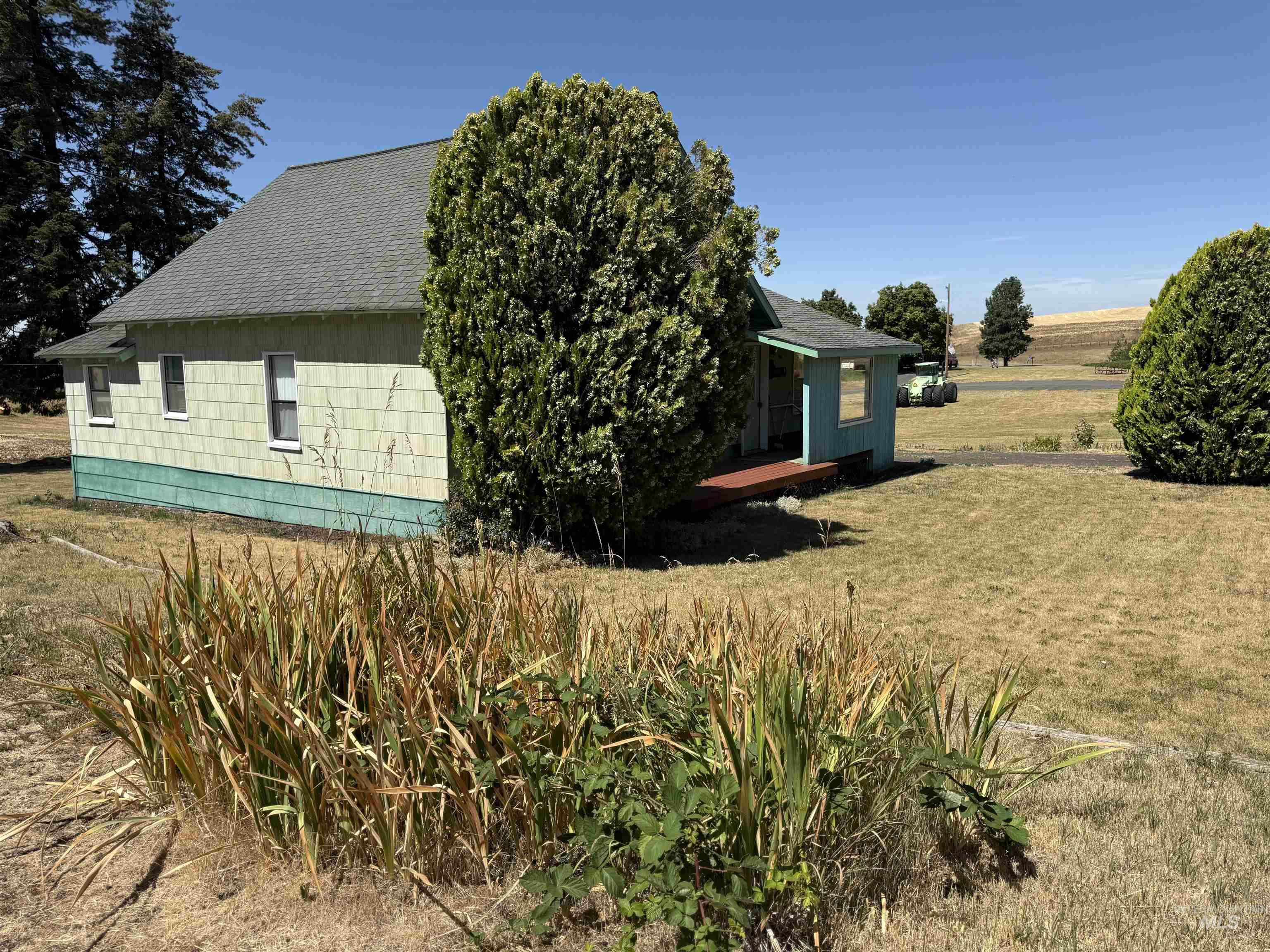 View of side of home featuring a yard, a shingled roof, and a view of rural / pastoral area