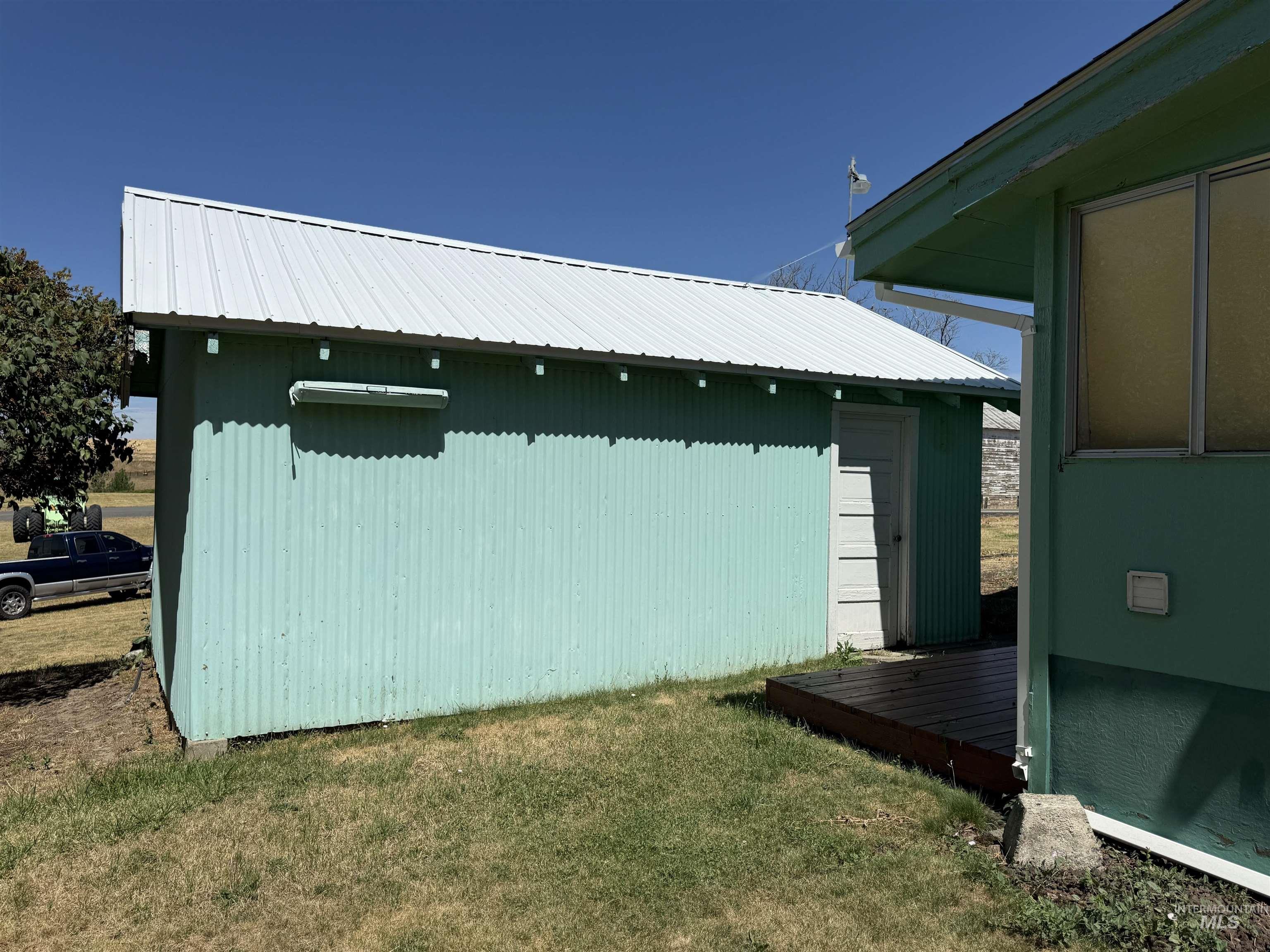 View of side of property featuring an outbuilding, a wooden deck, a yard, and a metal roof