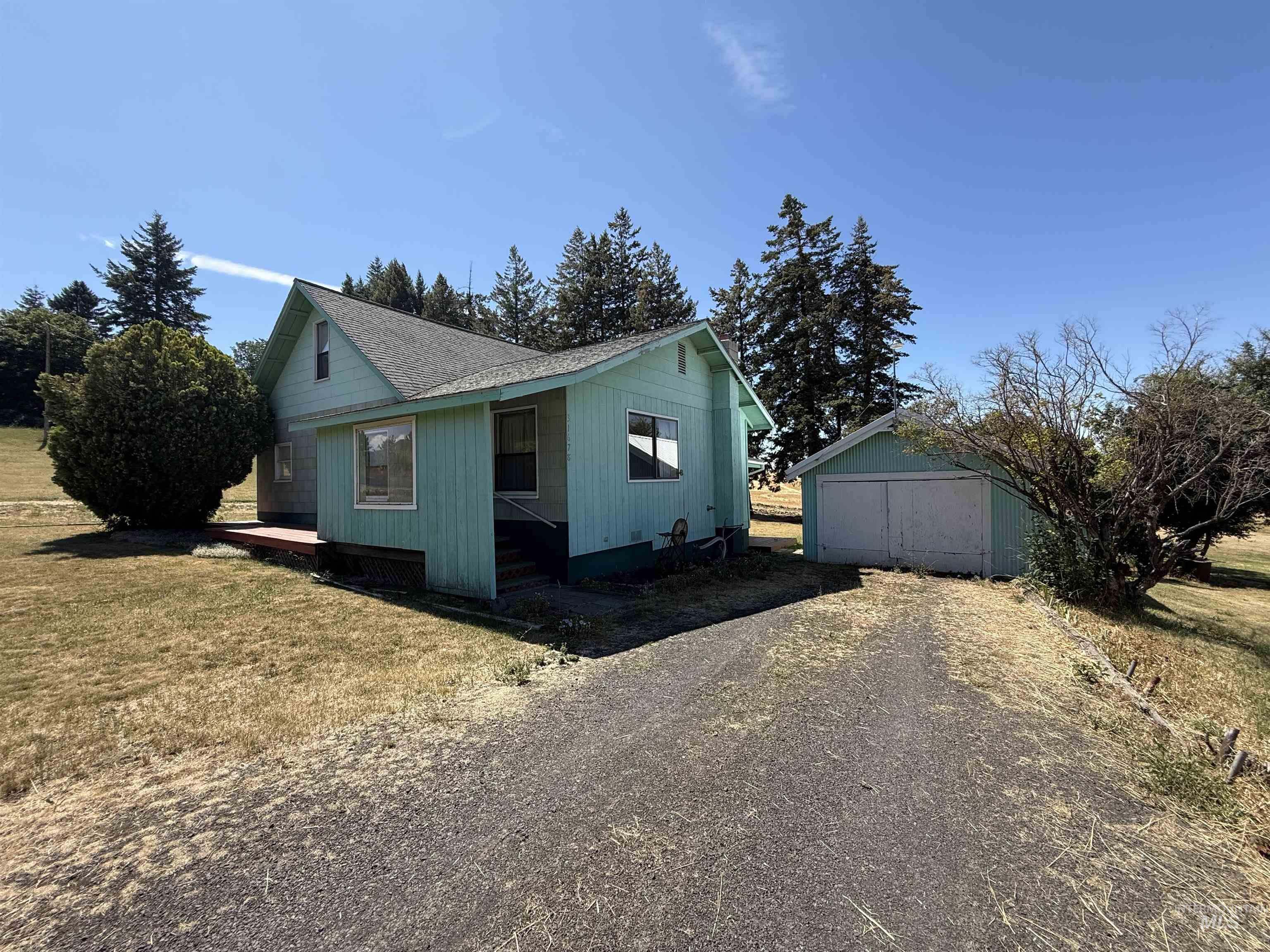 View of side of home featuring an outbuilding, roof with shingles, driveway, and a lawn