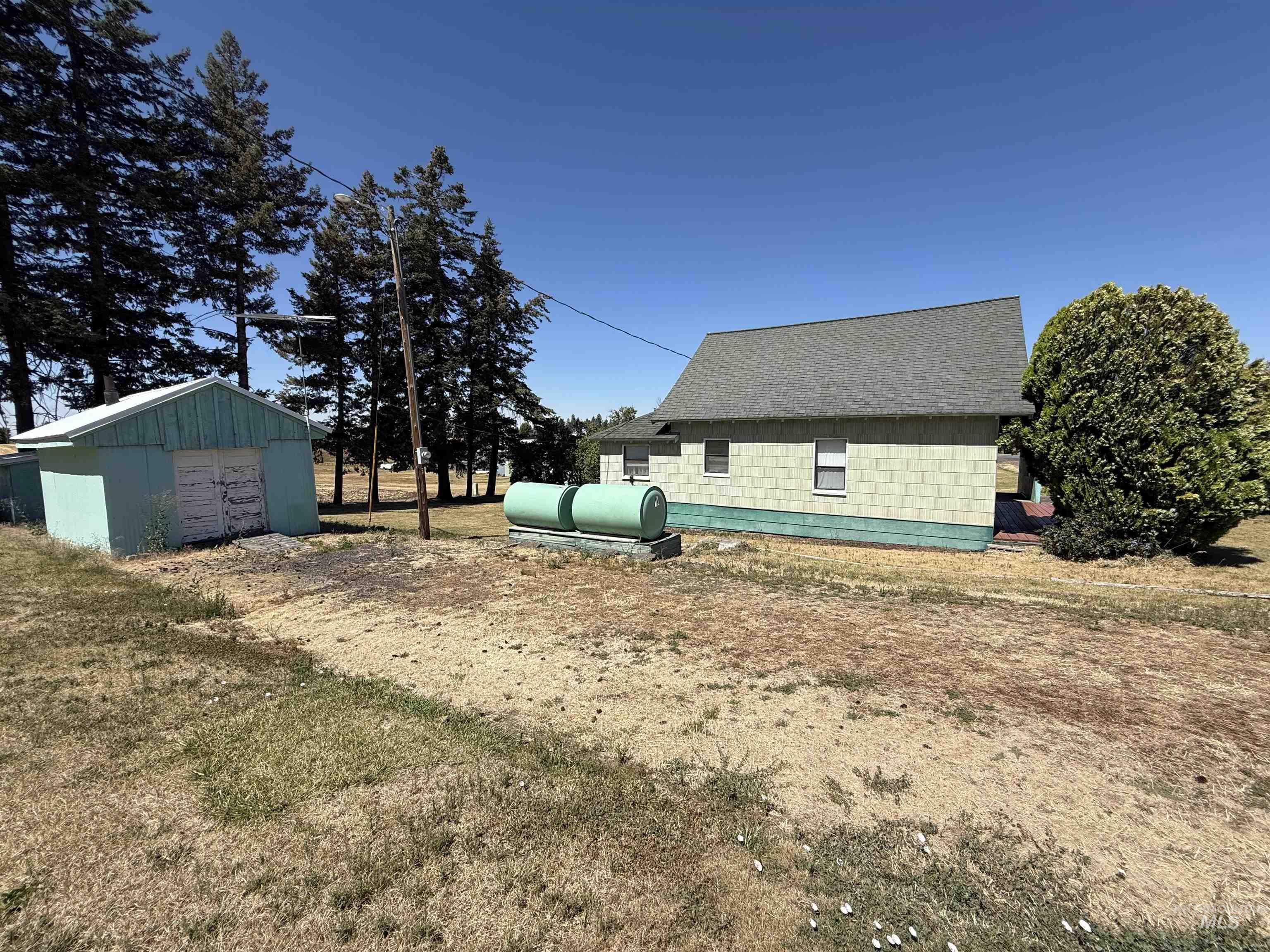View of property exterior featuring an outbuilding, concrete block siding, and roof with shingles