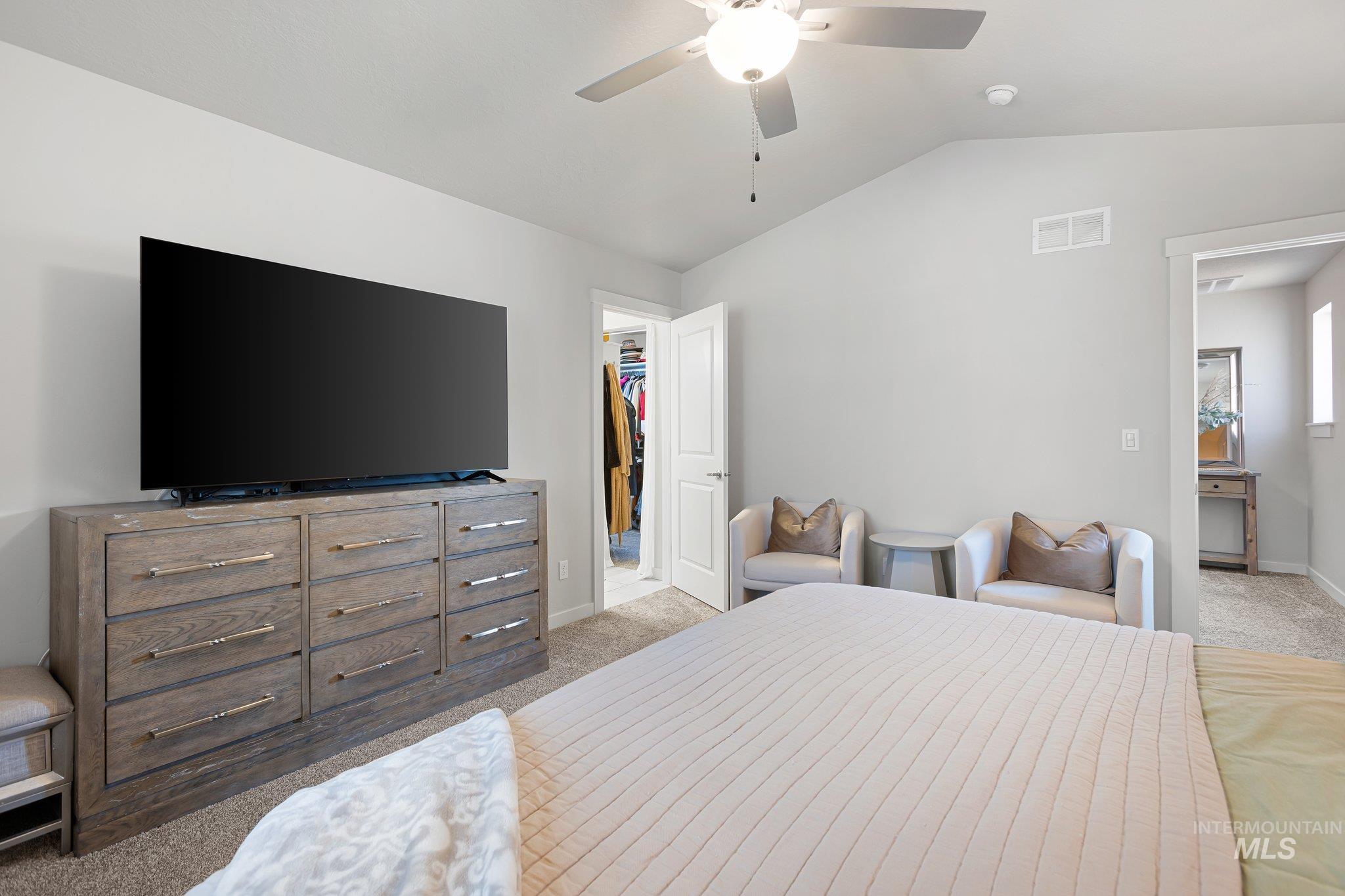 Bedroom with light colored carpet, lofted ceiling, a spacious closet, and a ceiling fan