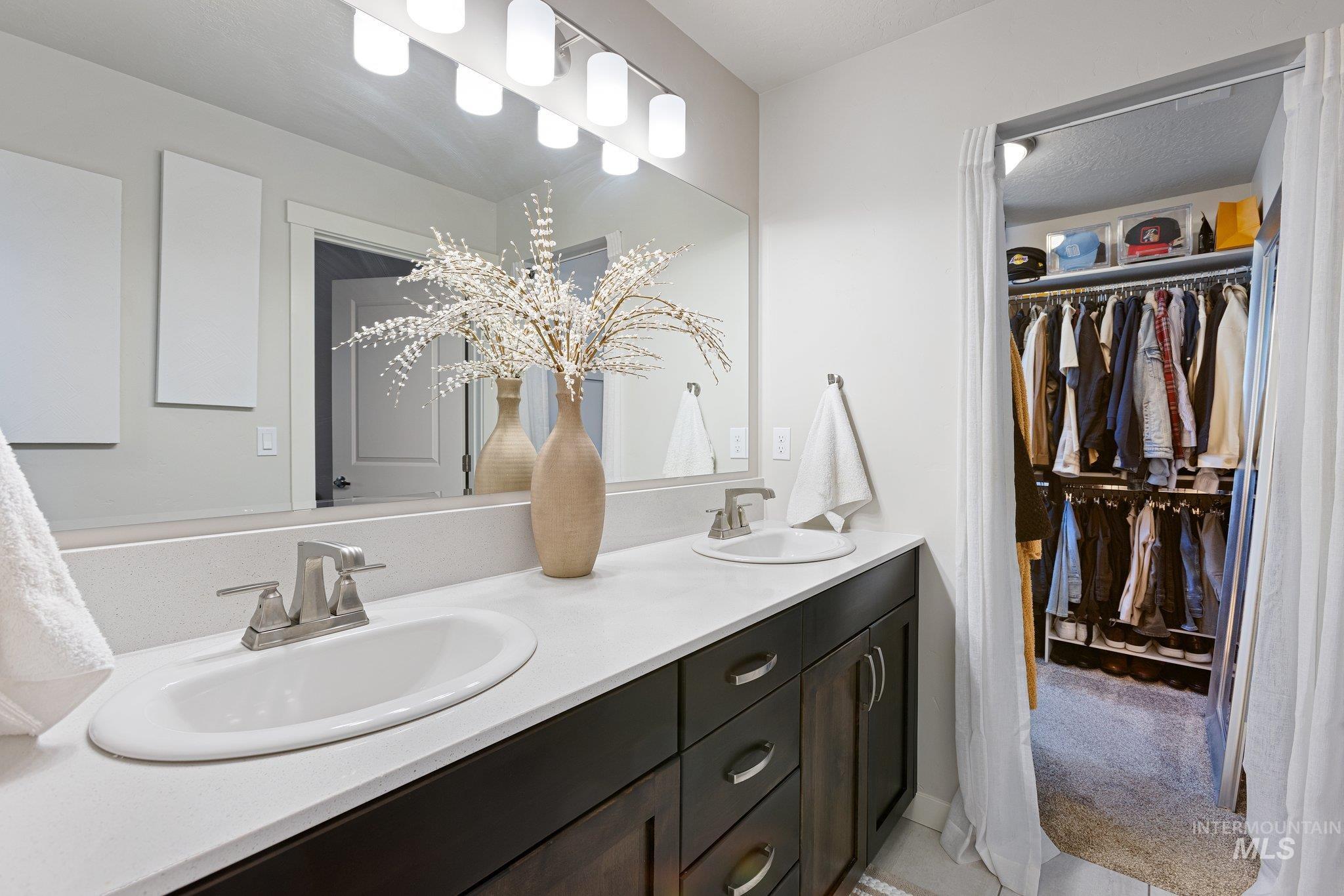 Bathroom featuring double vanity, a walk in closet, and light tile patterned floors