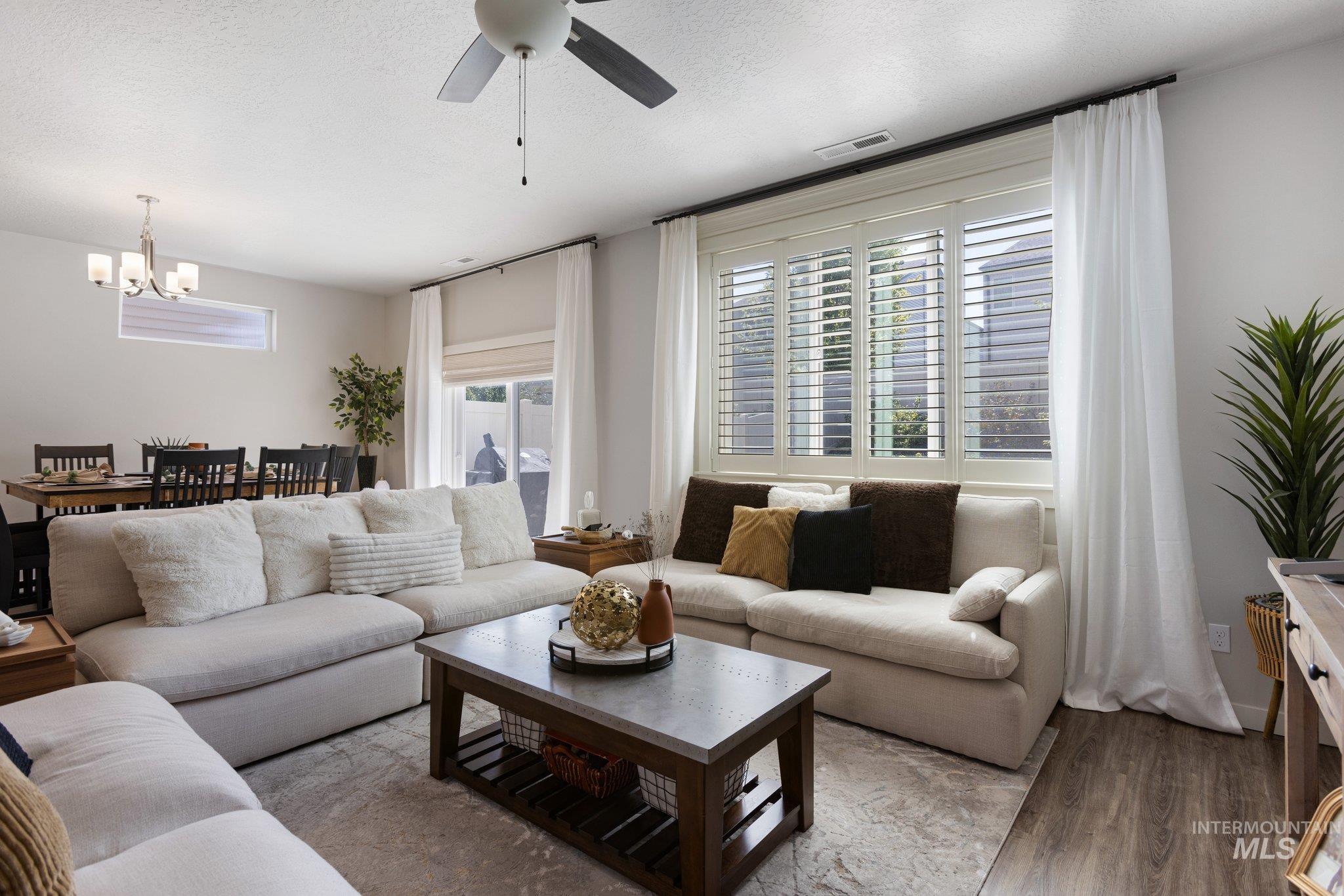 Living area with wood finished floors, a textured ceiling, ceiling fan, and a chandelier