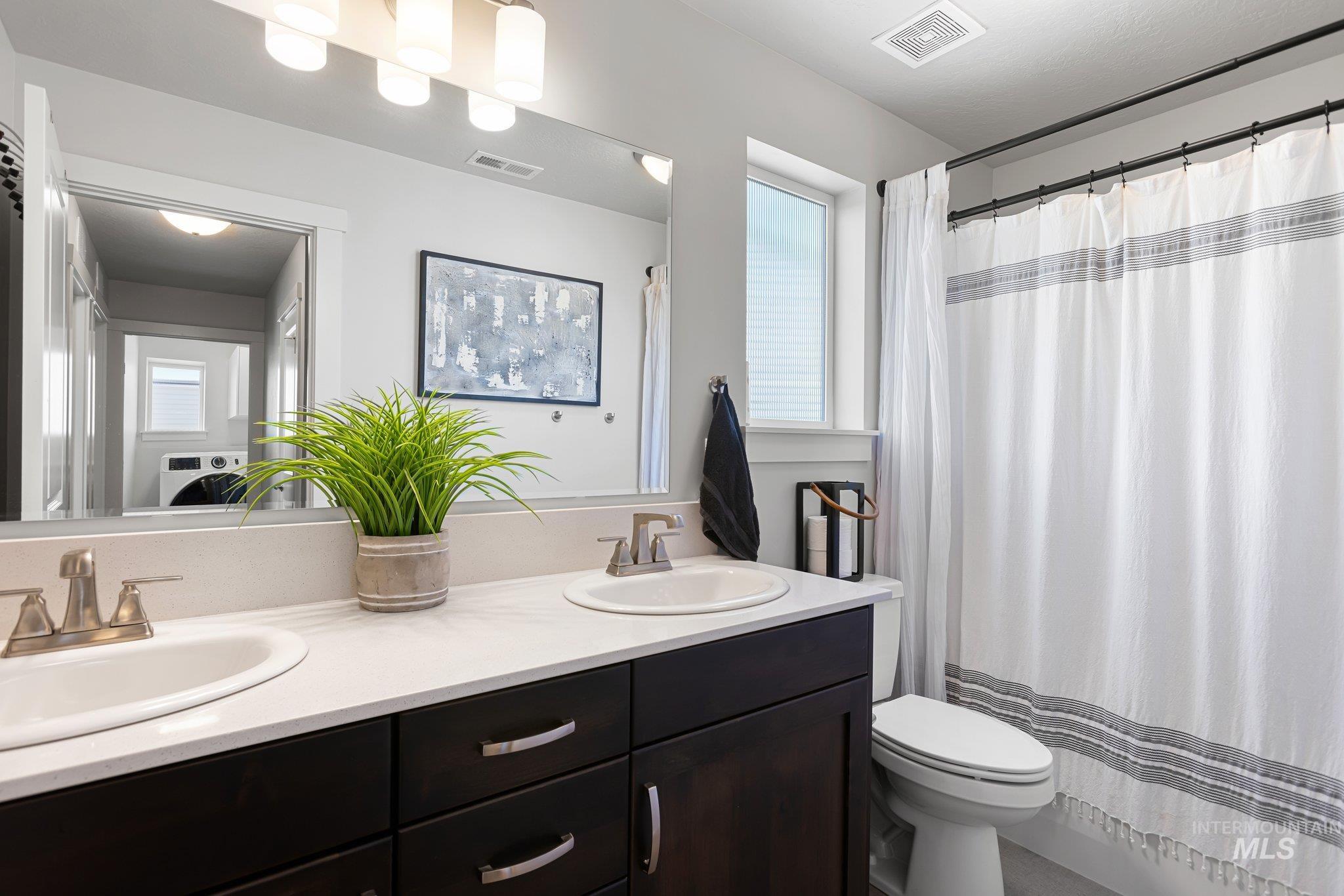 Bathroom featuring double vanity and curtained shower
