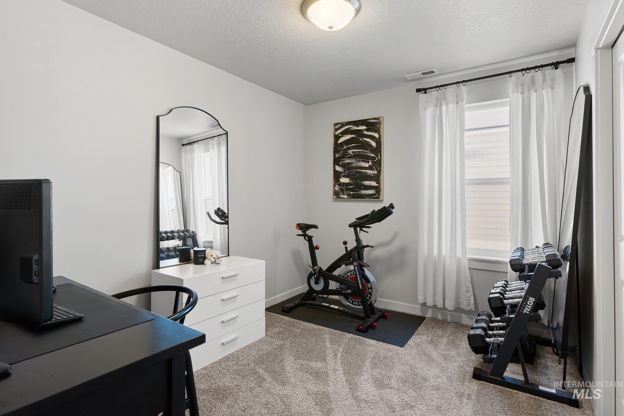 Home office with light carpet and a textured ceiling