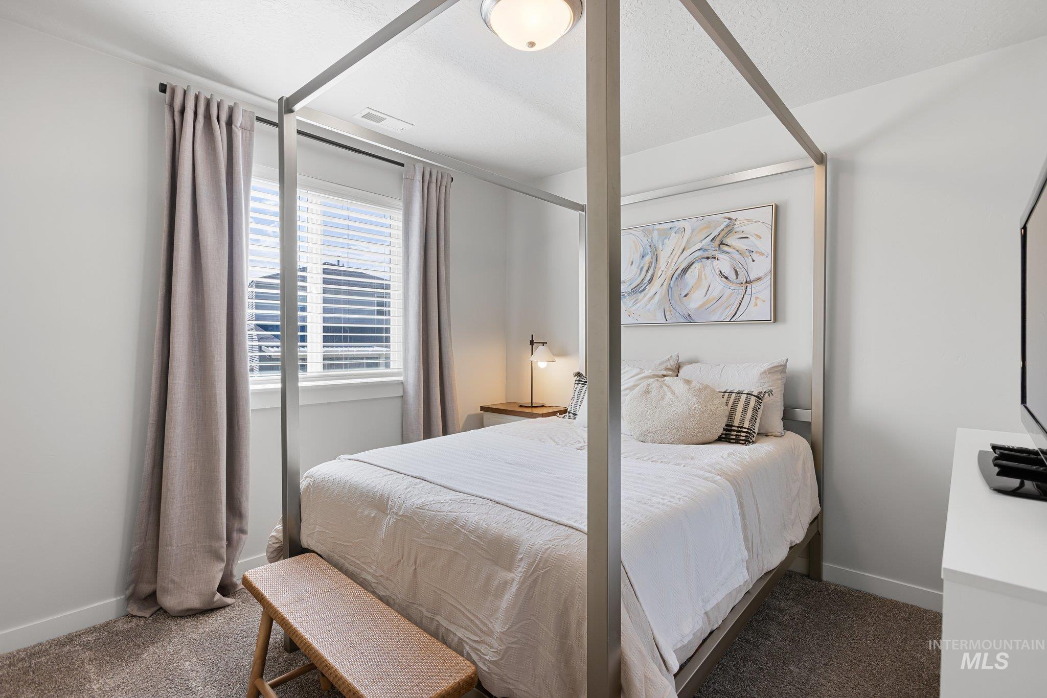 Bedroom with dark colored carpet and a textured ceiling