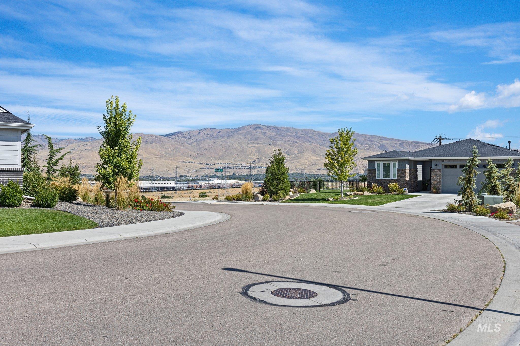 View of asphalt street with sidewalks, a mountain view, and curbs