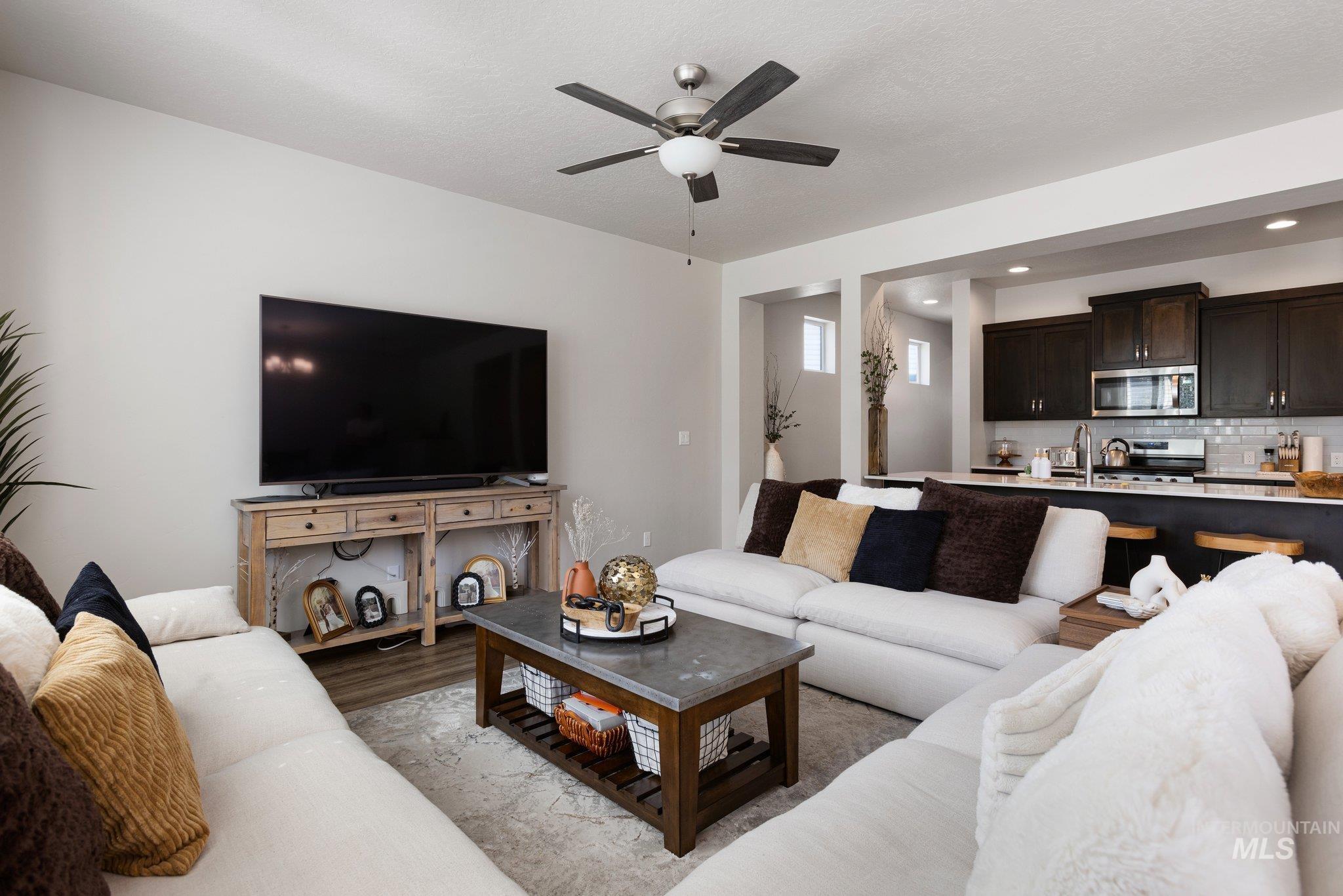Living room featuring light wood-style flooring, ceiling fan, and recessed lighting