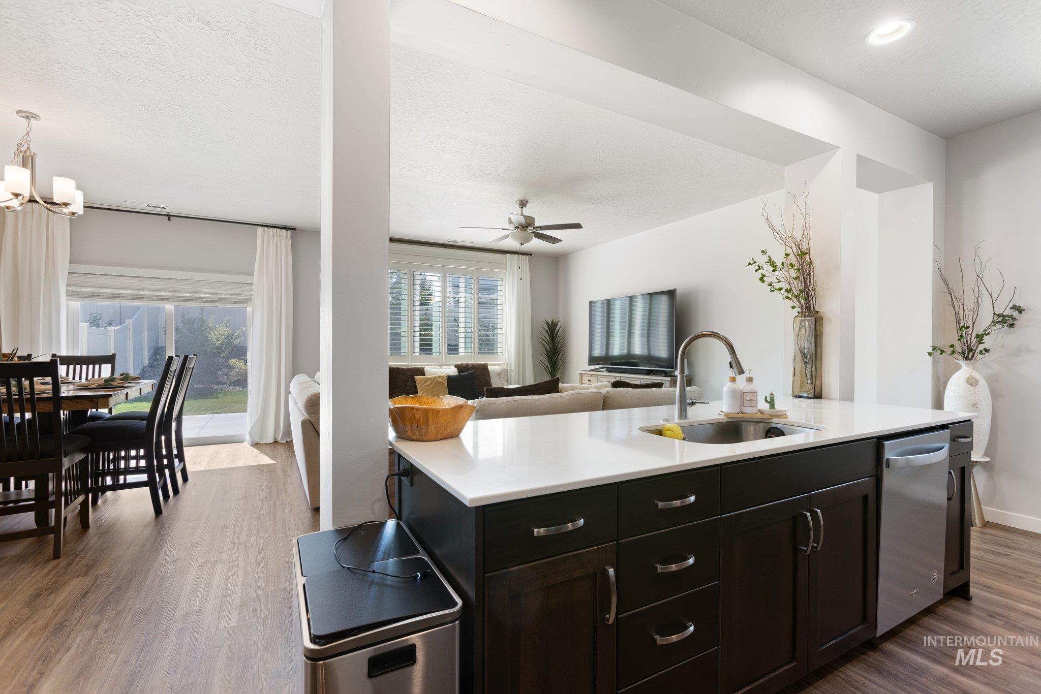 Kitchen with dark wood-style floors, healthy amount of natural light, open floor plan, a kitchen island with sink, and a textured ceiling