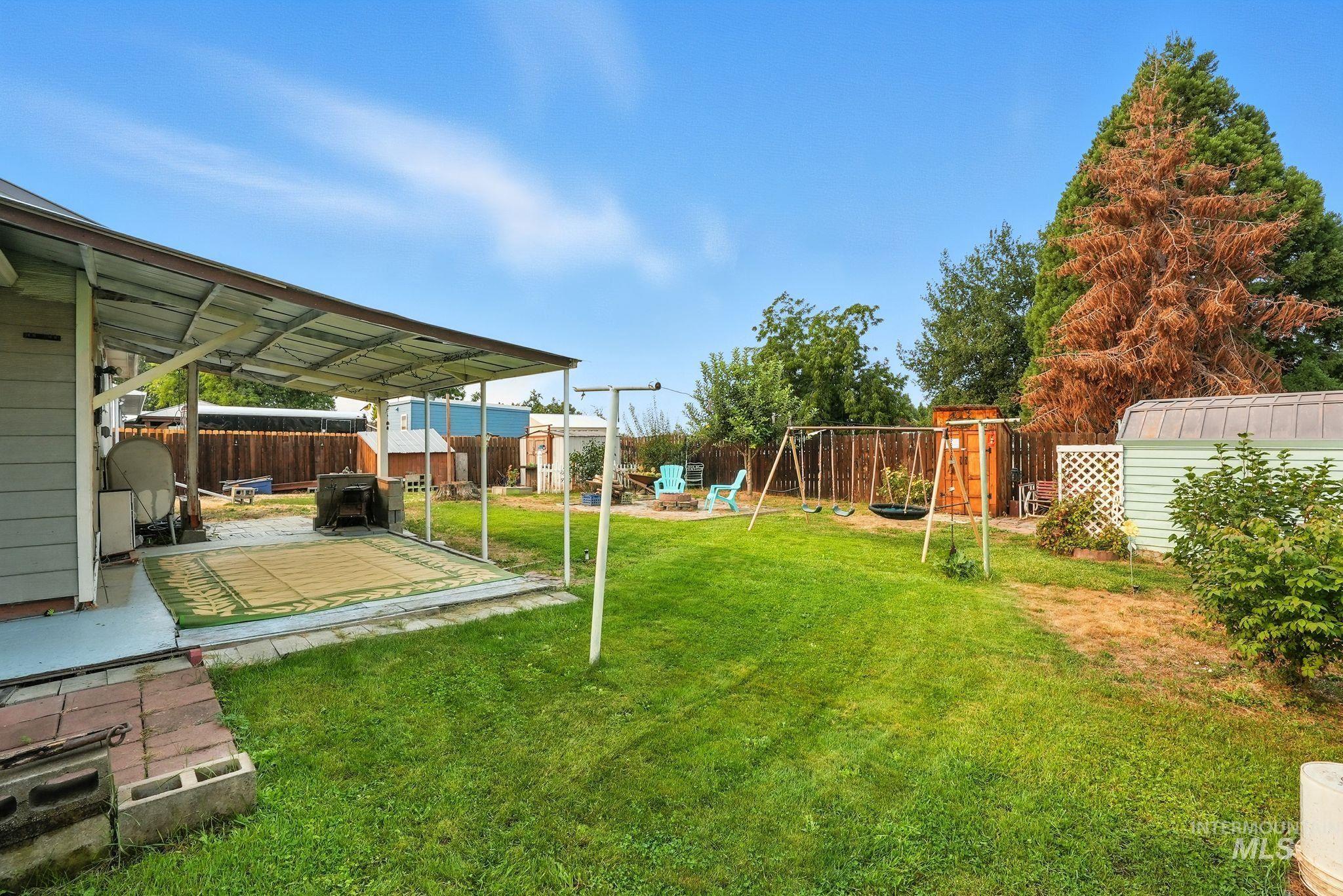 Fenced backyard featuring a playground, a patio area, and a storage shed