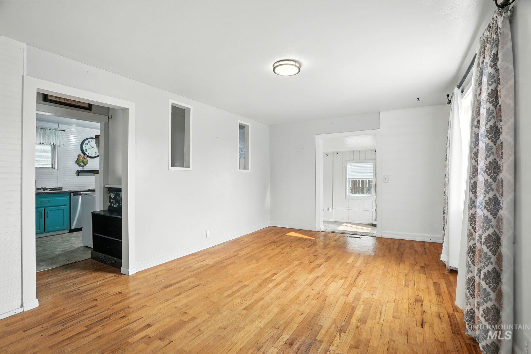 Unfurnished living room with light wood-style floors and baseboards