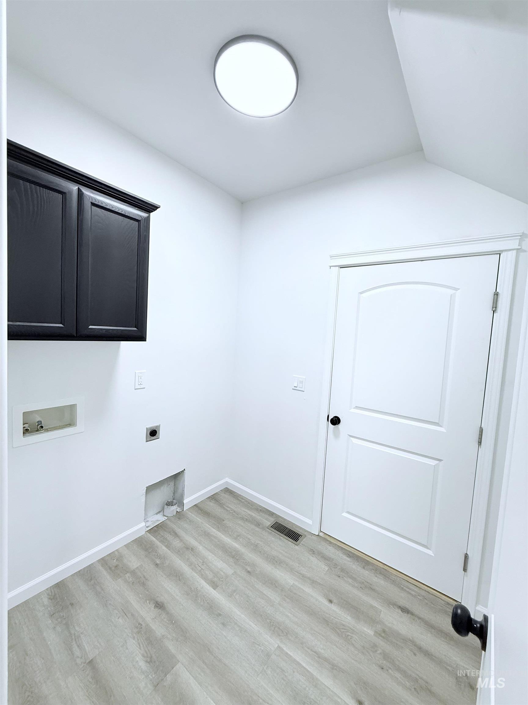 Washroom featuring washer hookup, electric dryer hookup, cabinet space, and light wood-style floors