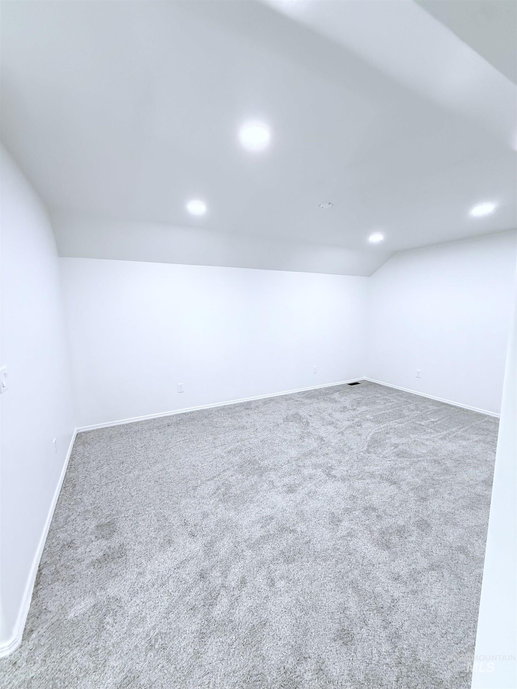 Carpeted empty room with recessed lighting and lofted ceiling