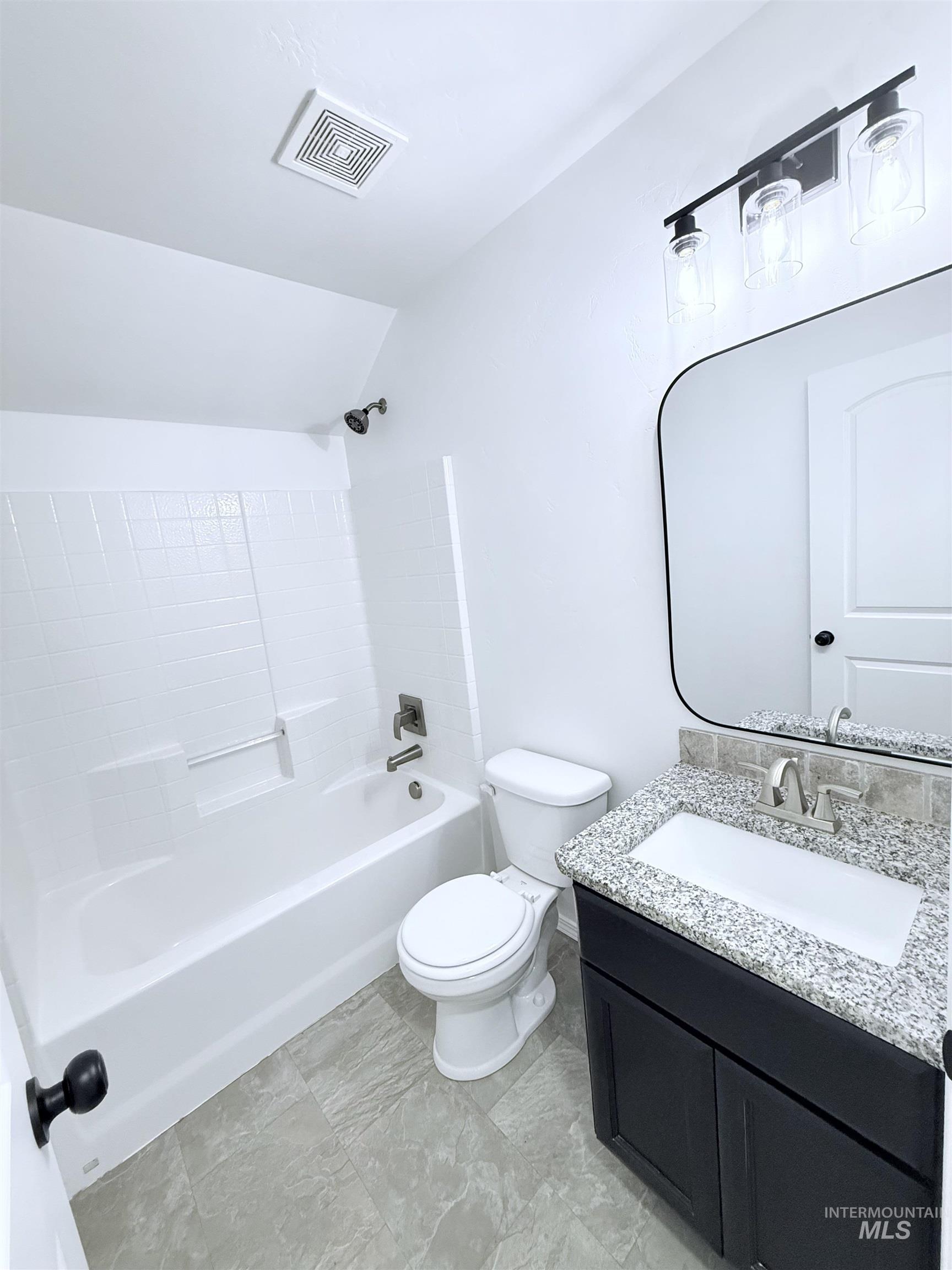 Bathroom featuring bathing tub / shower combination, vanity, and lofted ceiling