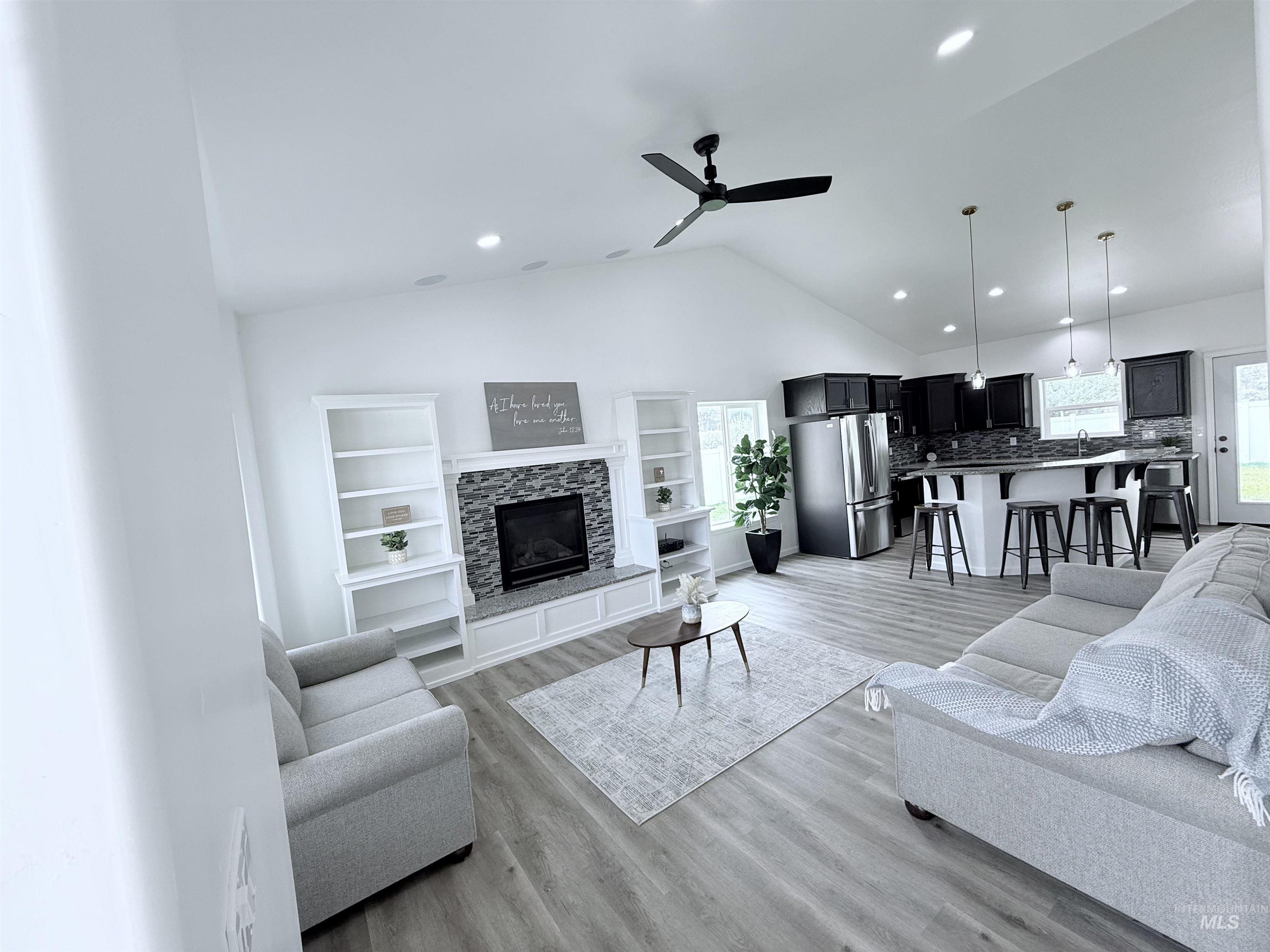Living area with lofted ceiling, light wood-style flooring, plenty of natural light, ceiling fan, and recessed lighting