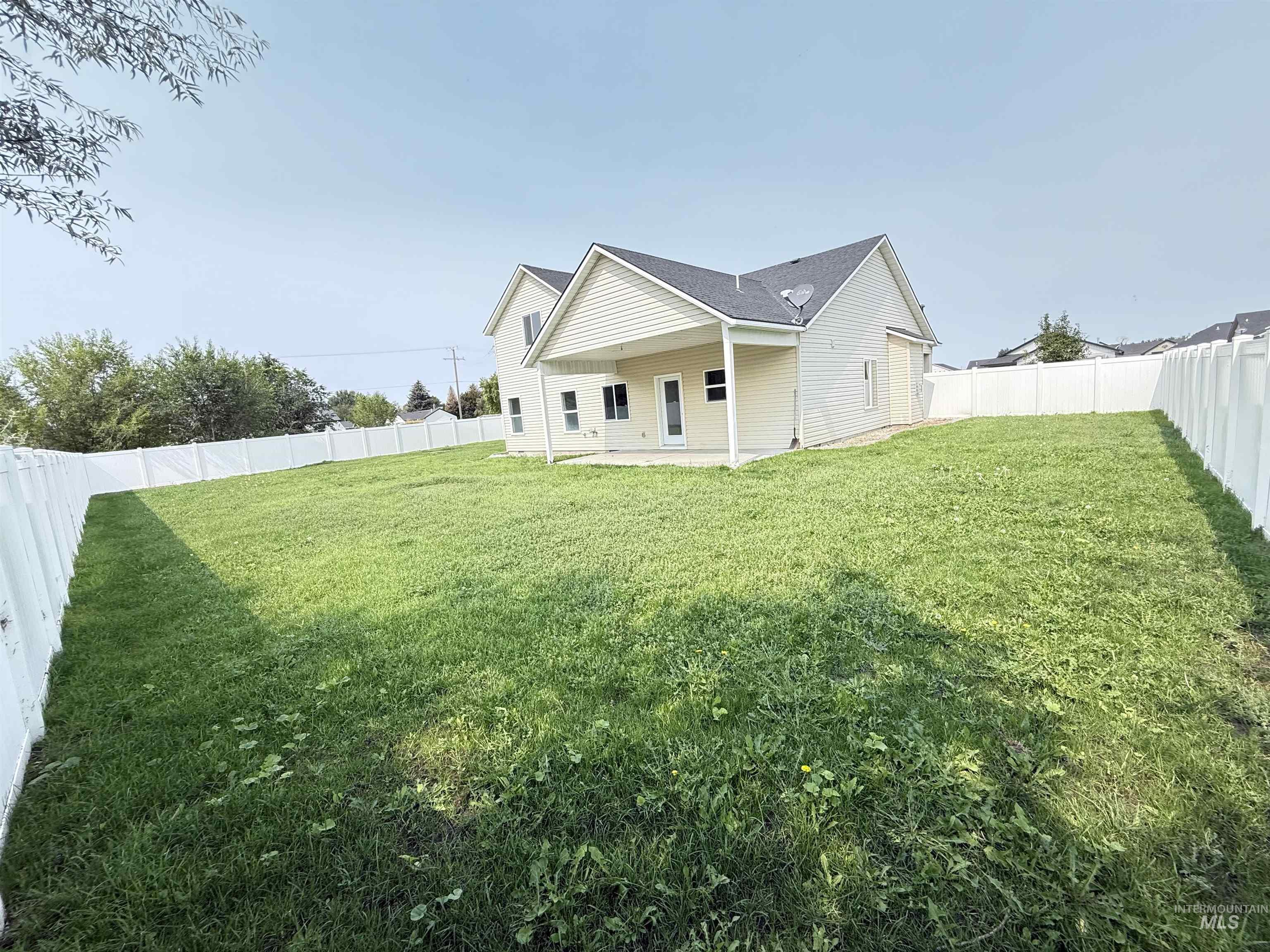Rear view of house with a patio area, a fenced backyard, and a shingled roof