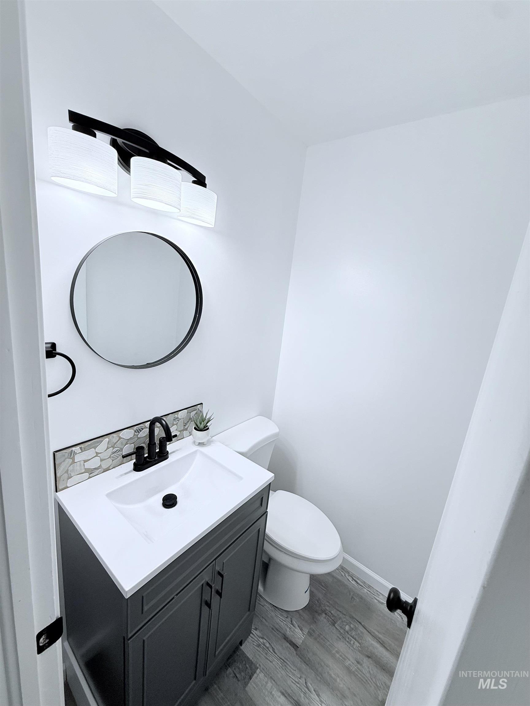 Half bath with light wood-style floors and vanity