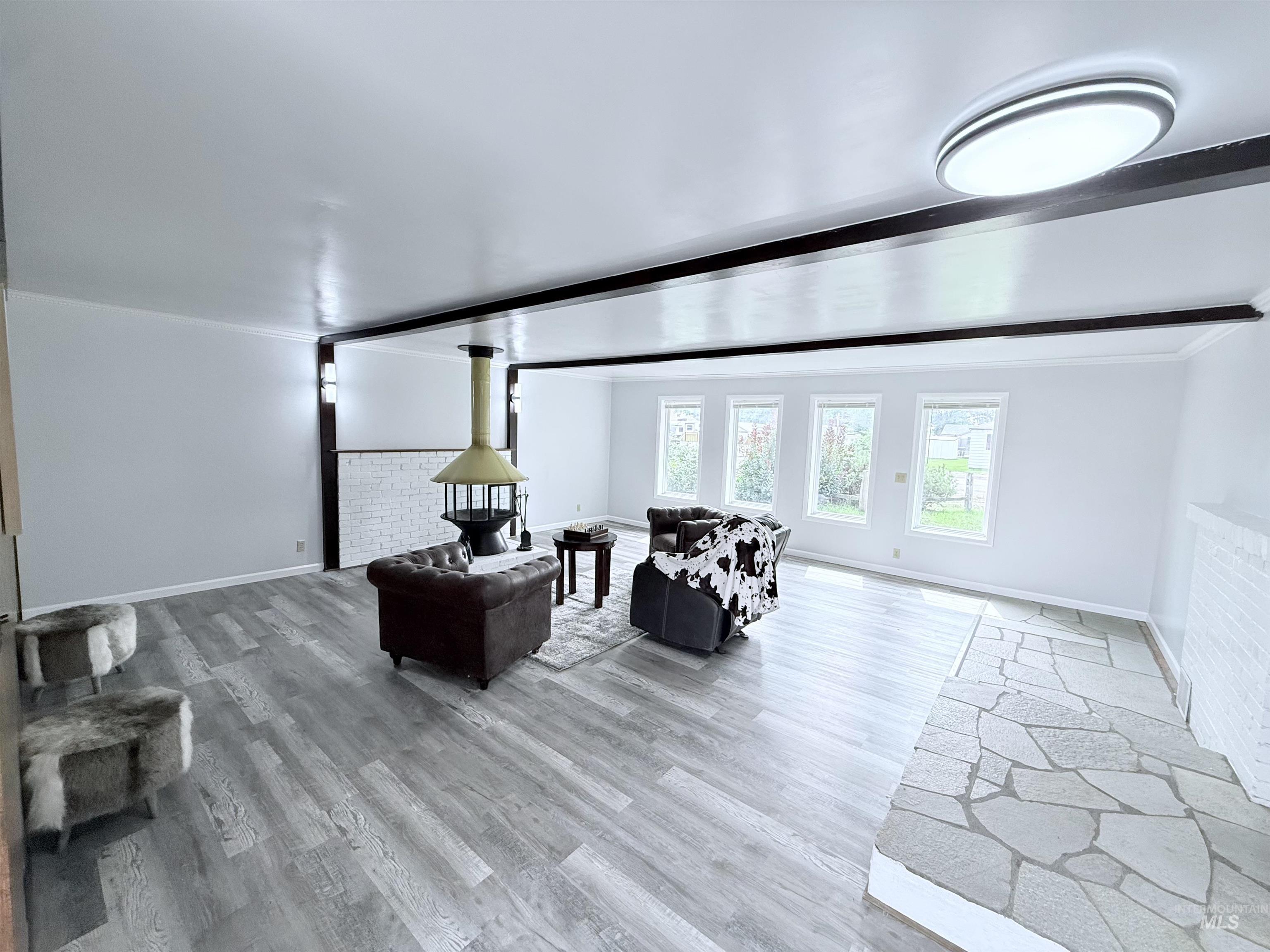 Living area featuring light wood-style floors, beam ceiling, and ornamental molding