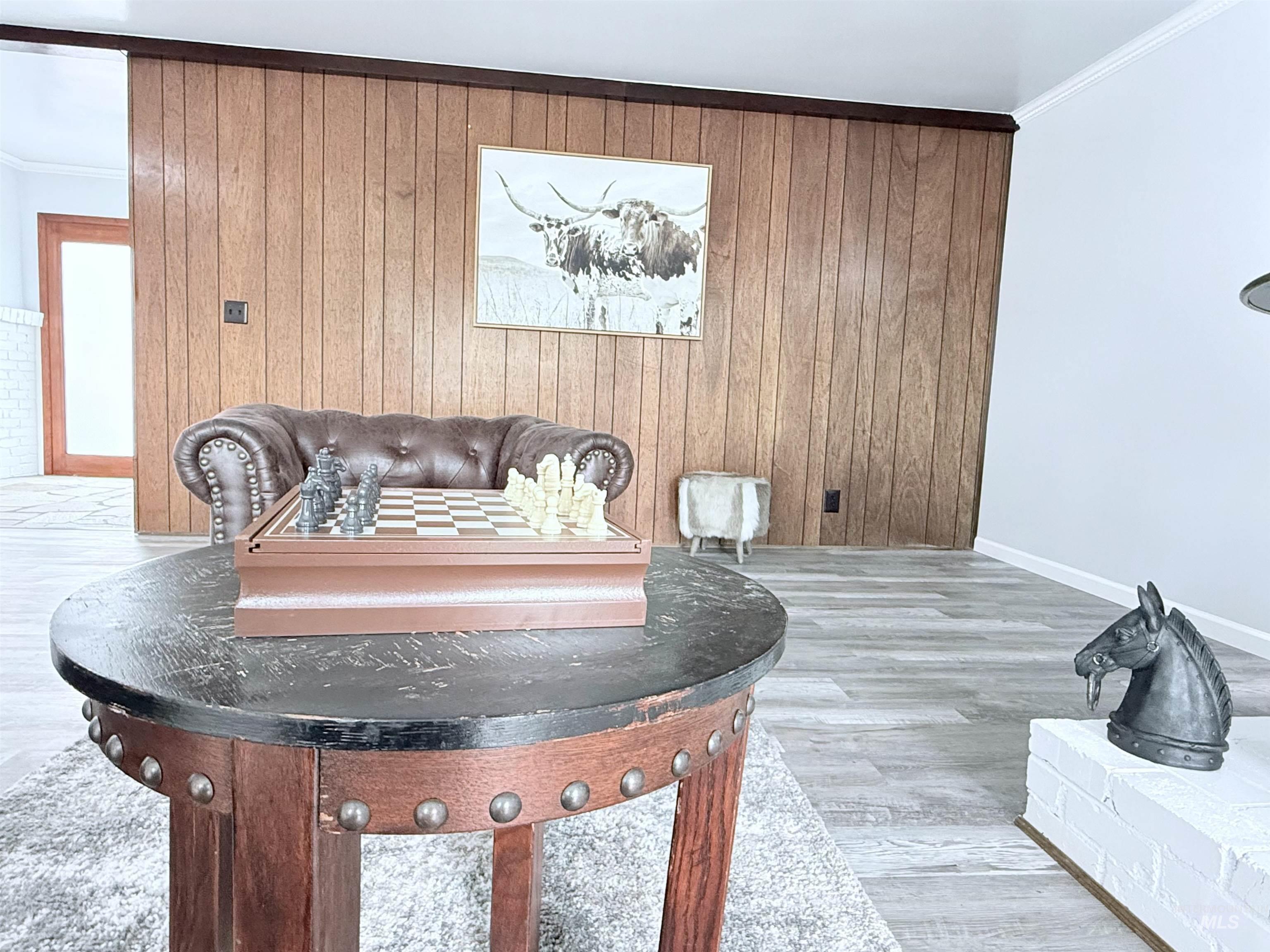 Detailed view of crown molding, wooden walls, and wood finished floors