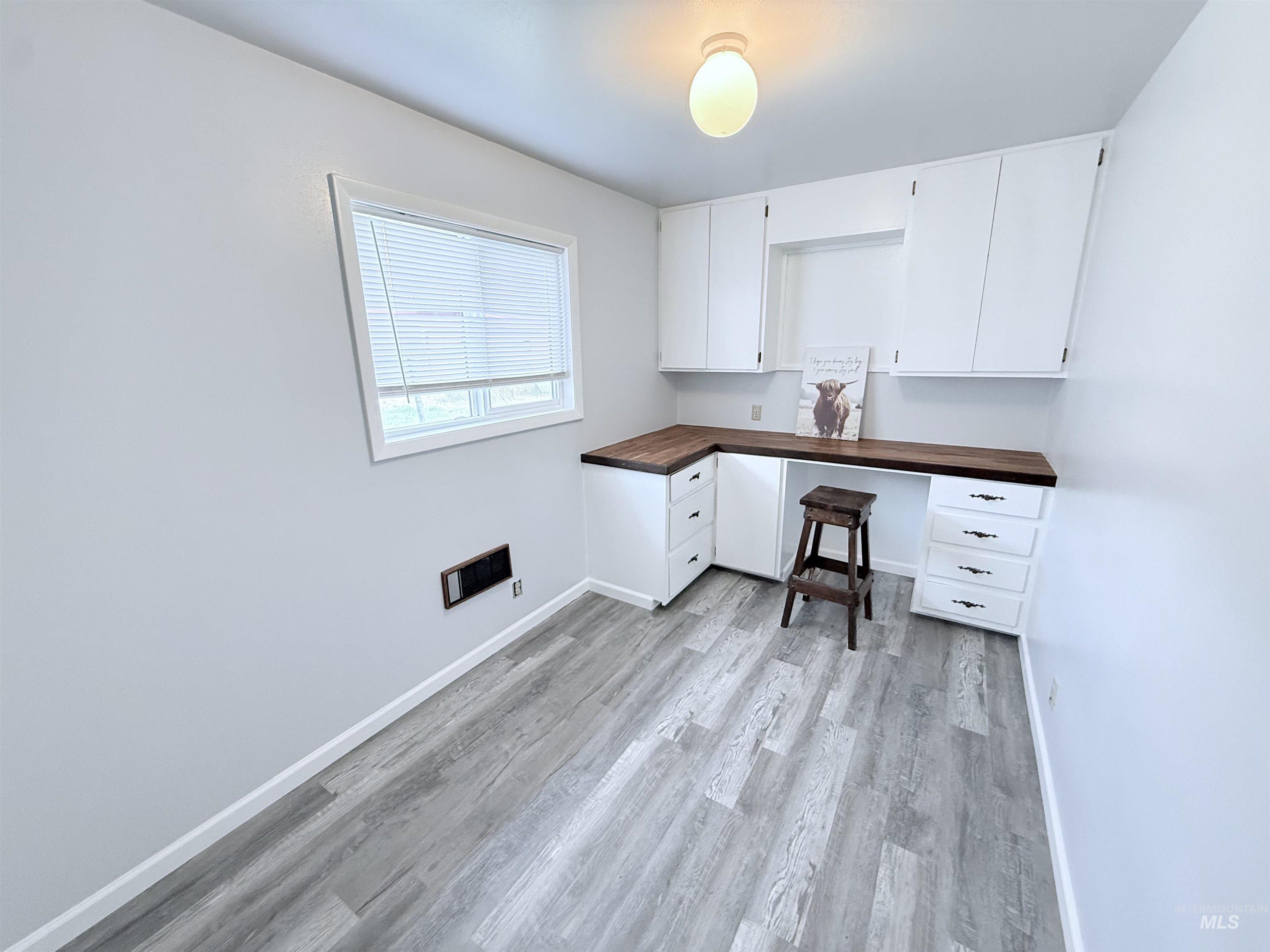Unfurnished office featuring light wood finished floors and built in study area