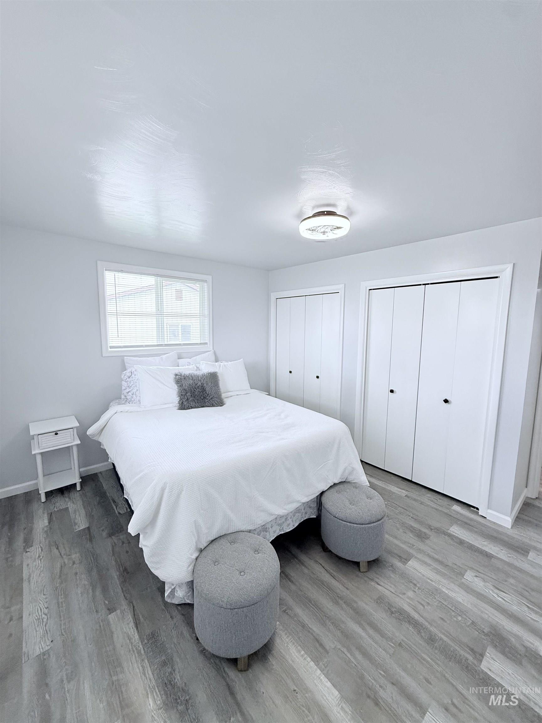 Bedroom with multiple closets and wood finished floors